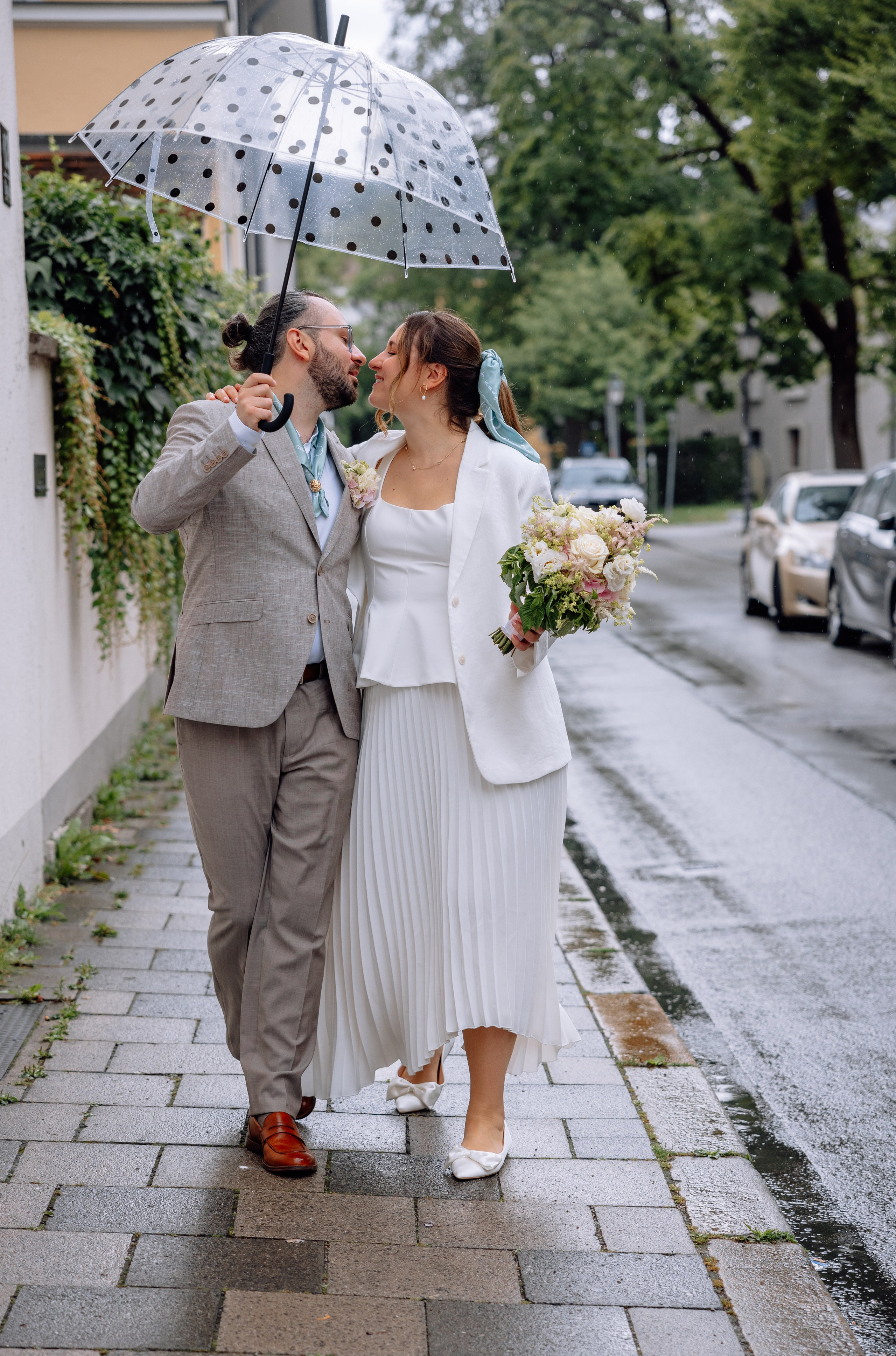 Brautpaar umarmt sich im Regen – romantische Stimmung vor Standesamt Schwabing