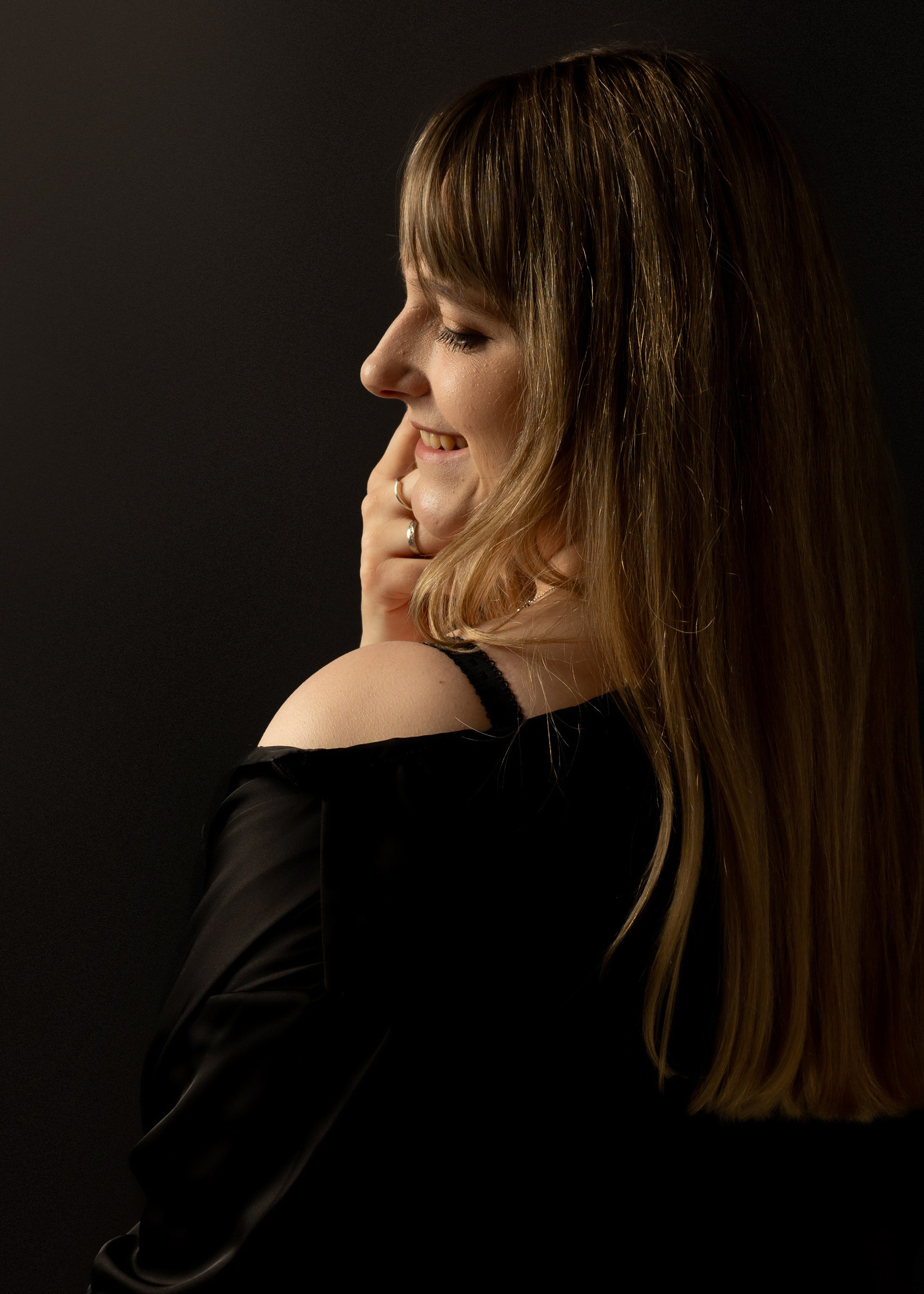 "Junge Frau umarmt sich selbst, mit einem sanften Lächeln auf den Lippen."