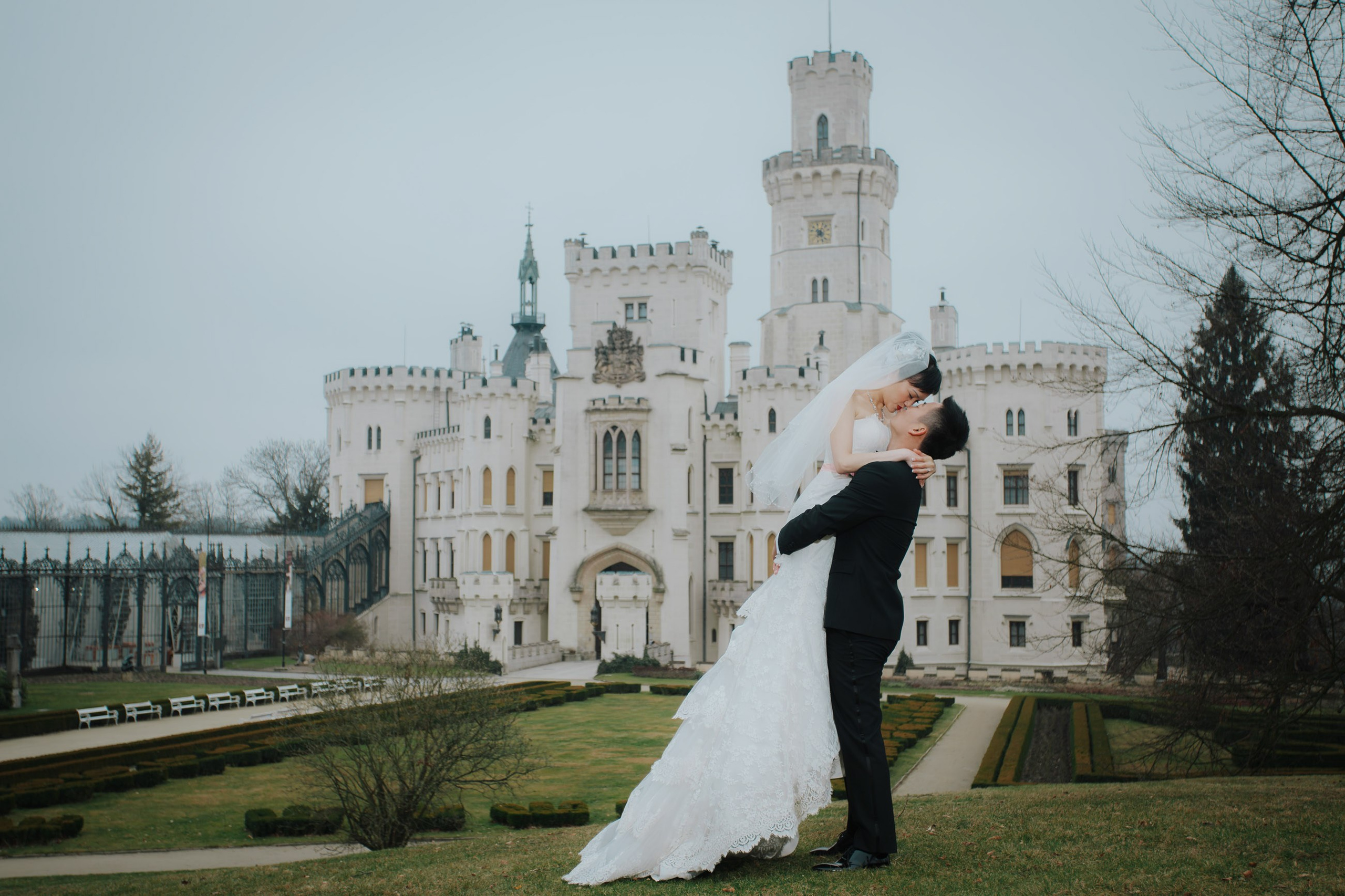 A Hong Kong groom picks up his bride and spins her around culminating in a dramatic kiss against the backdrop of the historic Castle Hluboka where they had earlier held their intimate destination wedding.