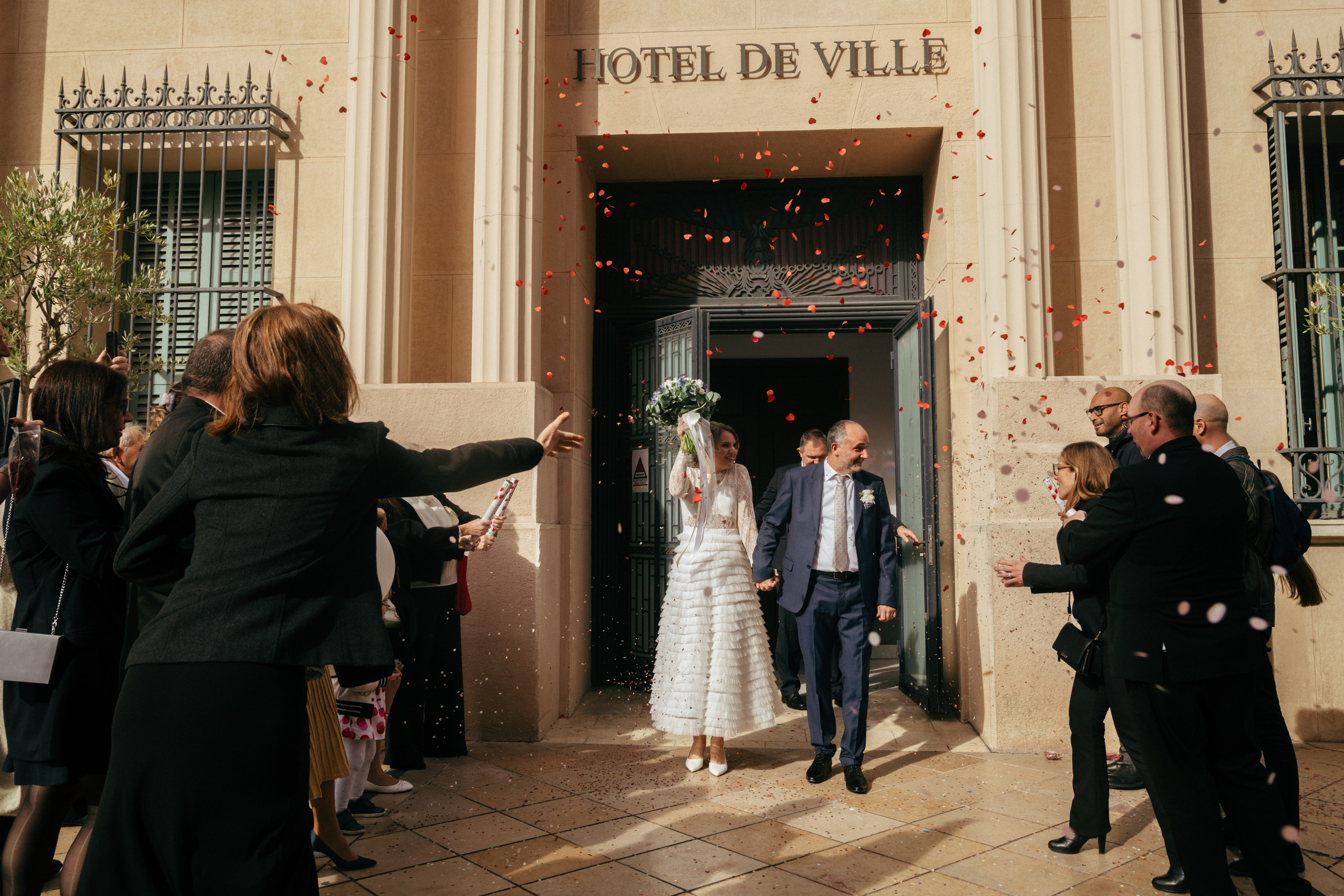 Молодожёны выходят из мэрии, а гости осыпают их конфетти.
