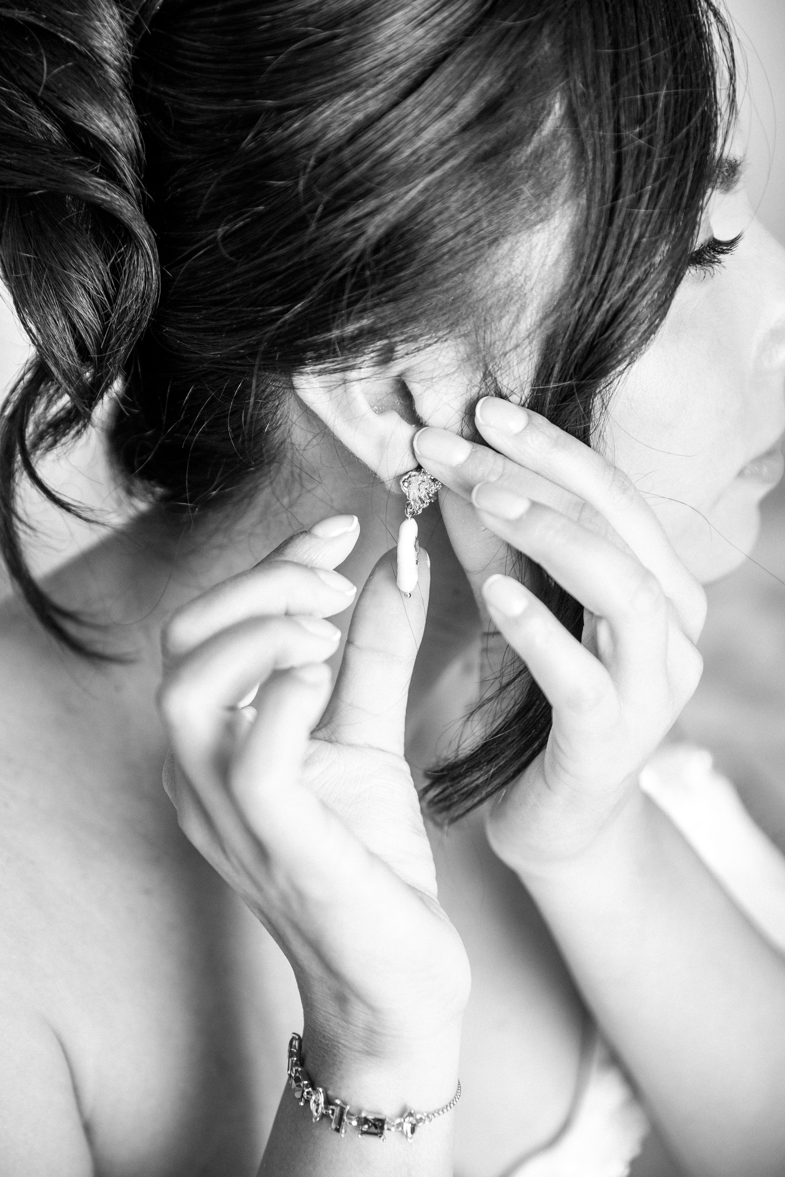 Candid shot of the bride adjusting her earrings before the wedding ceremony