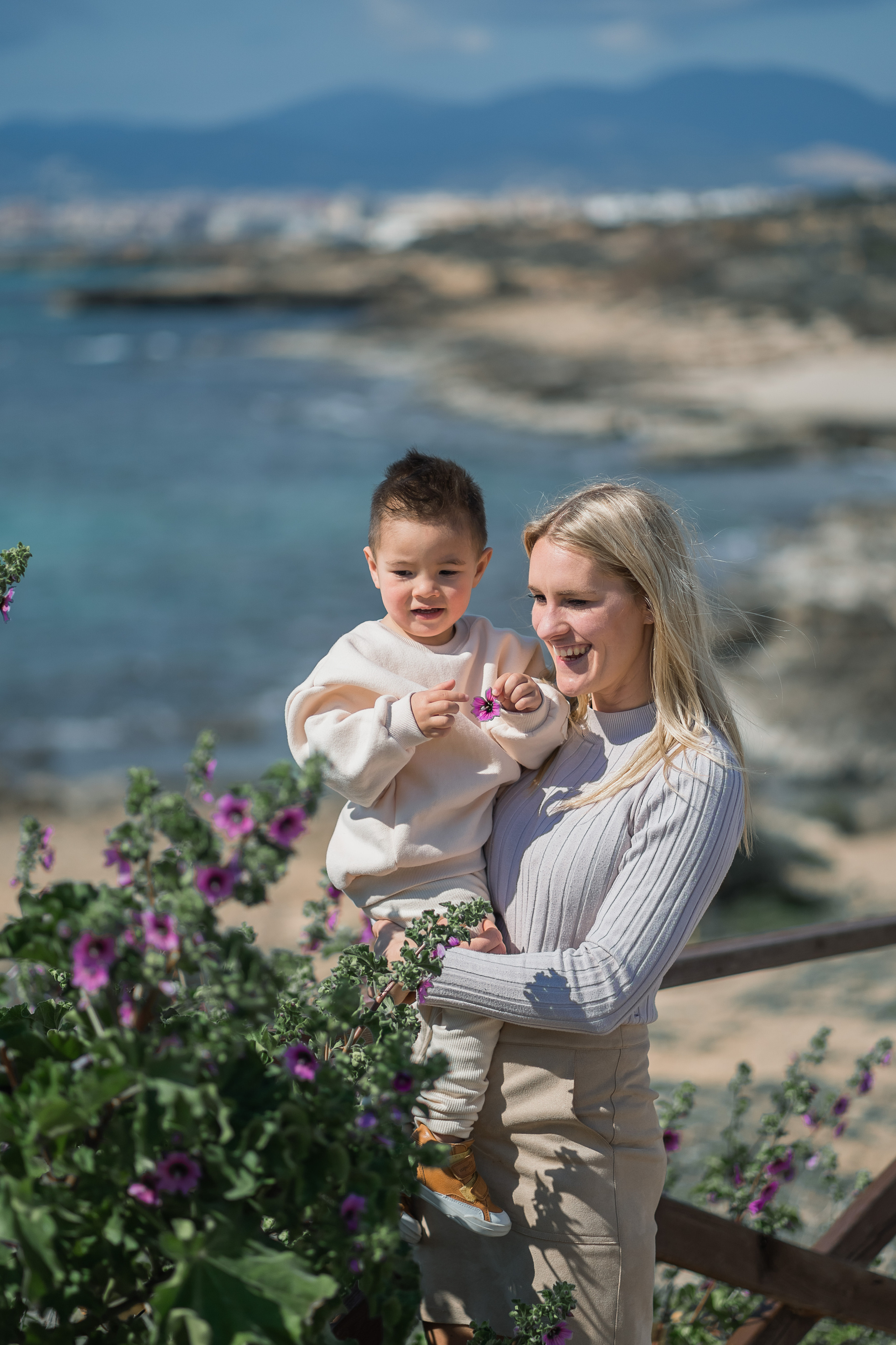 Eine Frau, die ihr Kind am Strand von Palma de Mallorca trägt.