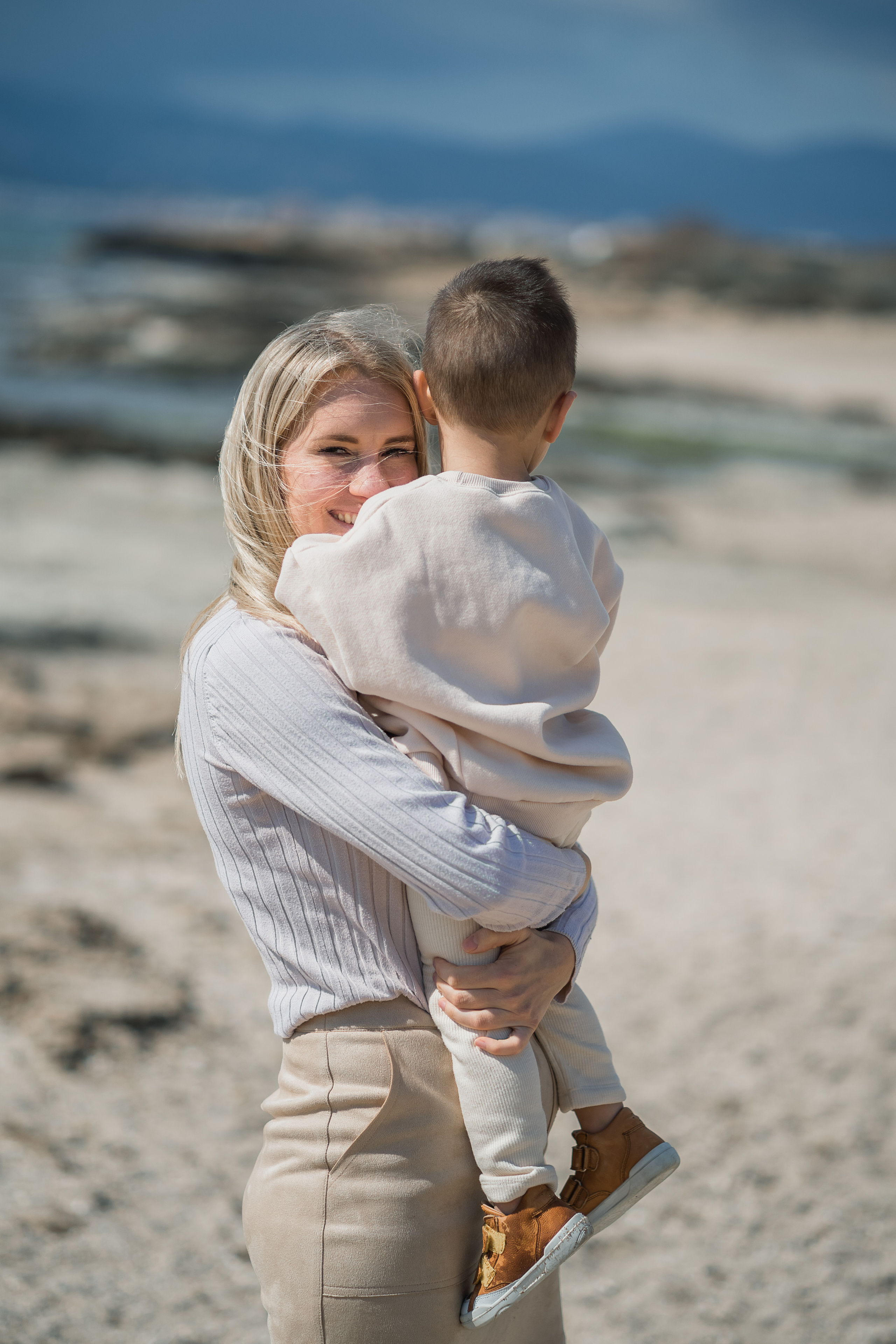 Eine Mutter, die mit ihrem Sohn am Strand von Arenal auf Mallorca kuschelt