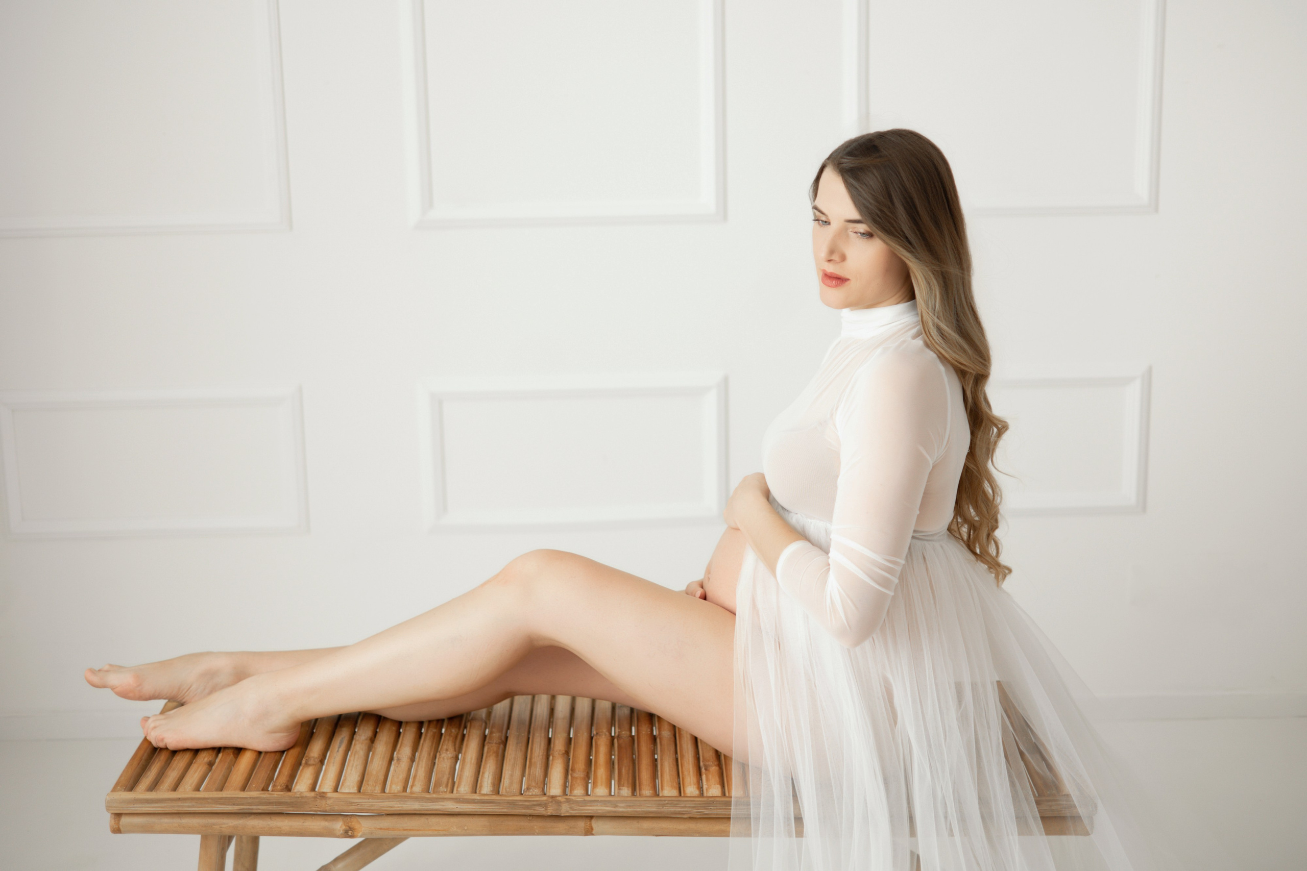 Elegantes Schwangerschaftsshooting im Sitzen – Frau mit stolzem Blick auf ihren Babybauch in Dortmund.