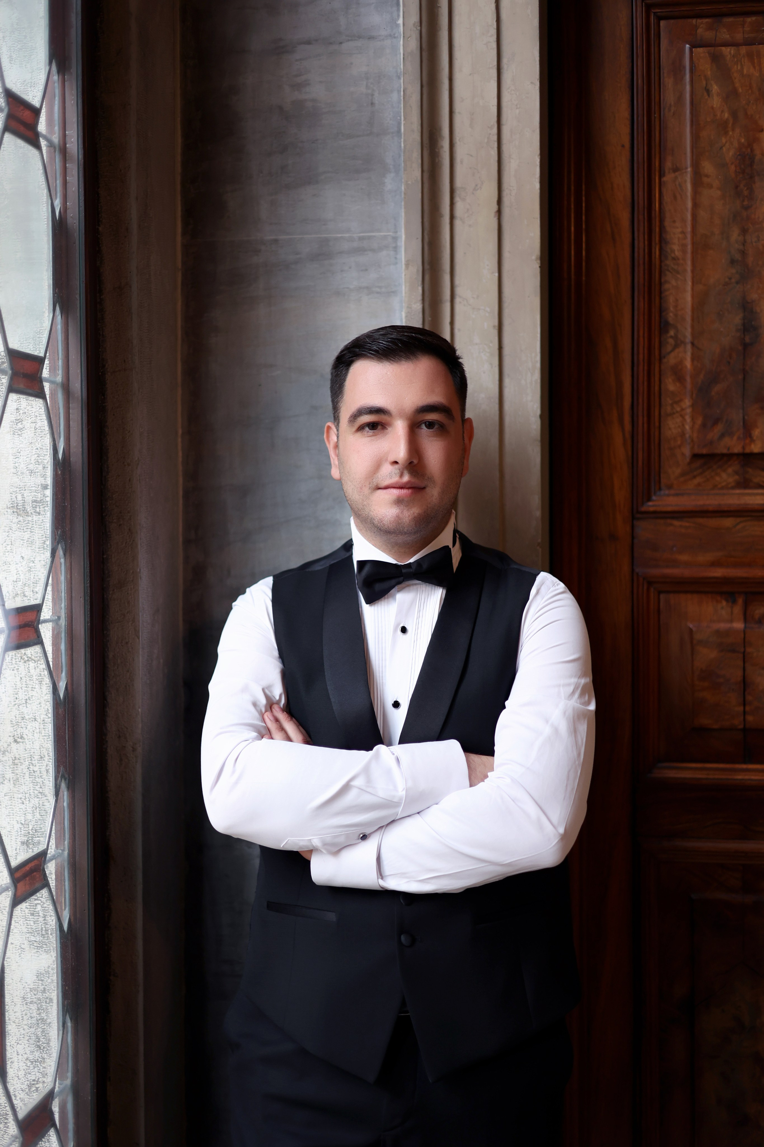 Armenian groom in white dress standing in the serene courtyard of Aman Venice
