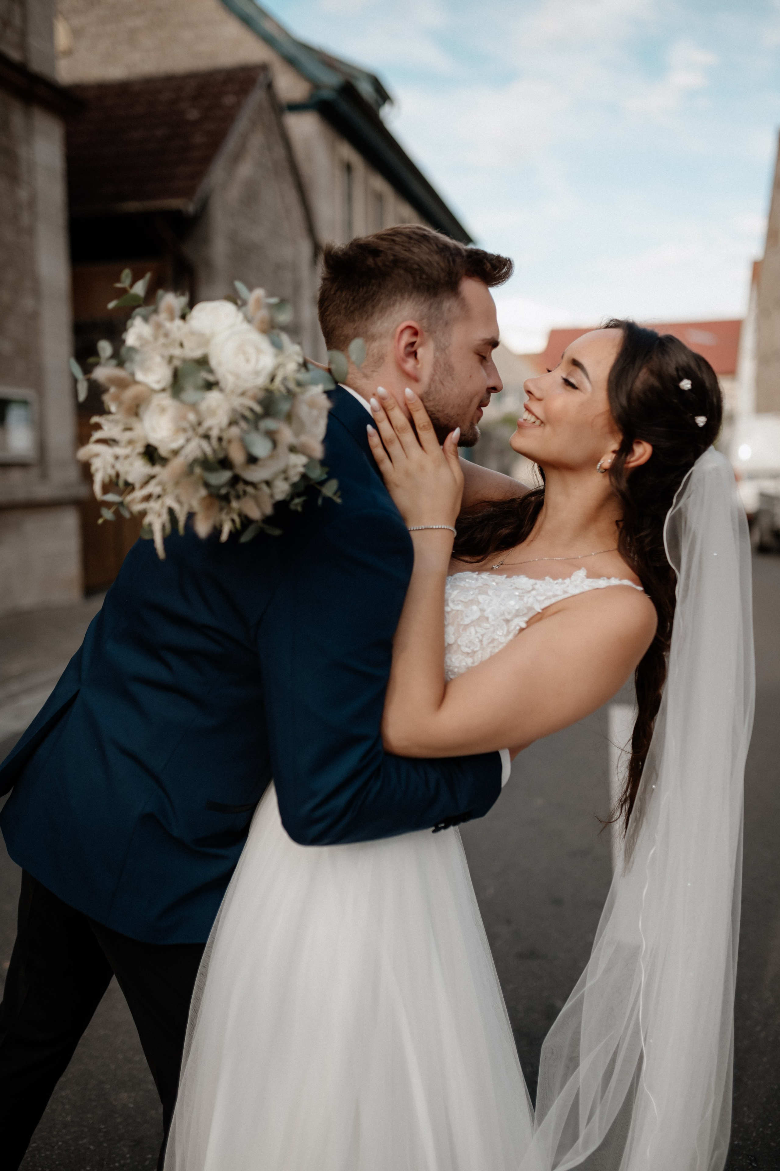 Brautpaar küsst sich vor dem Landhaus – Verträumter Moment in rustikaler Umgebung