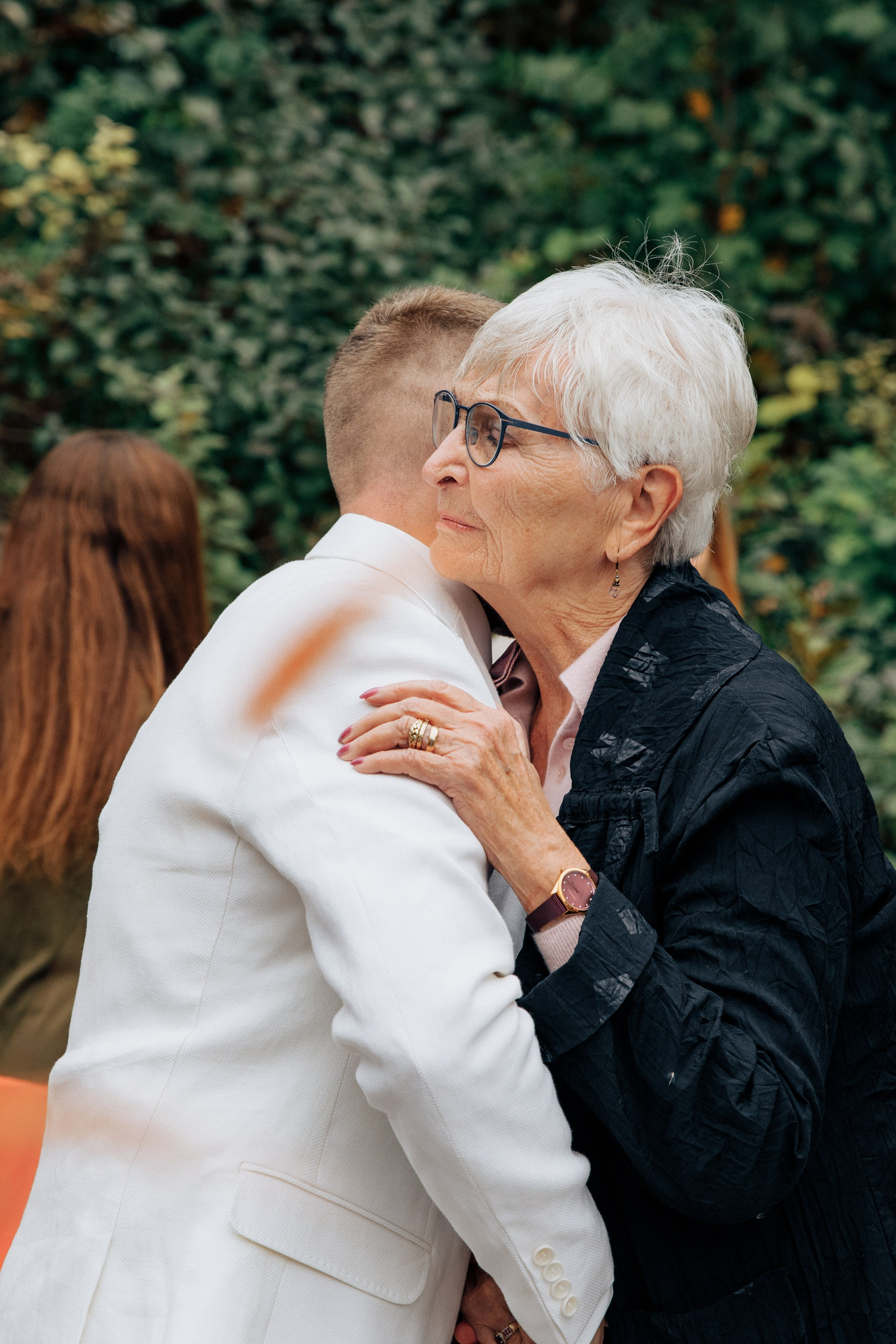 Die Großmutter umarmt den Bräutigam.