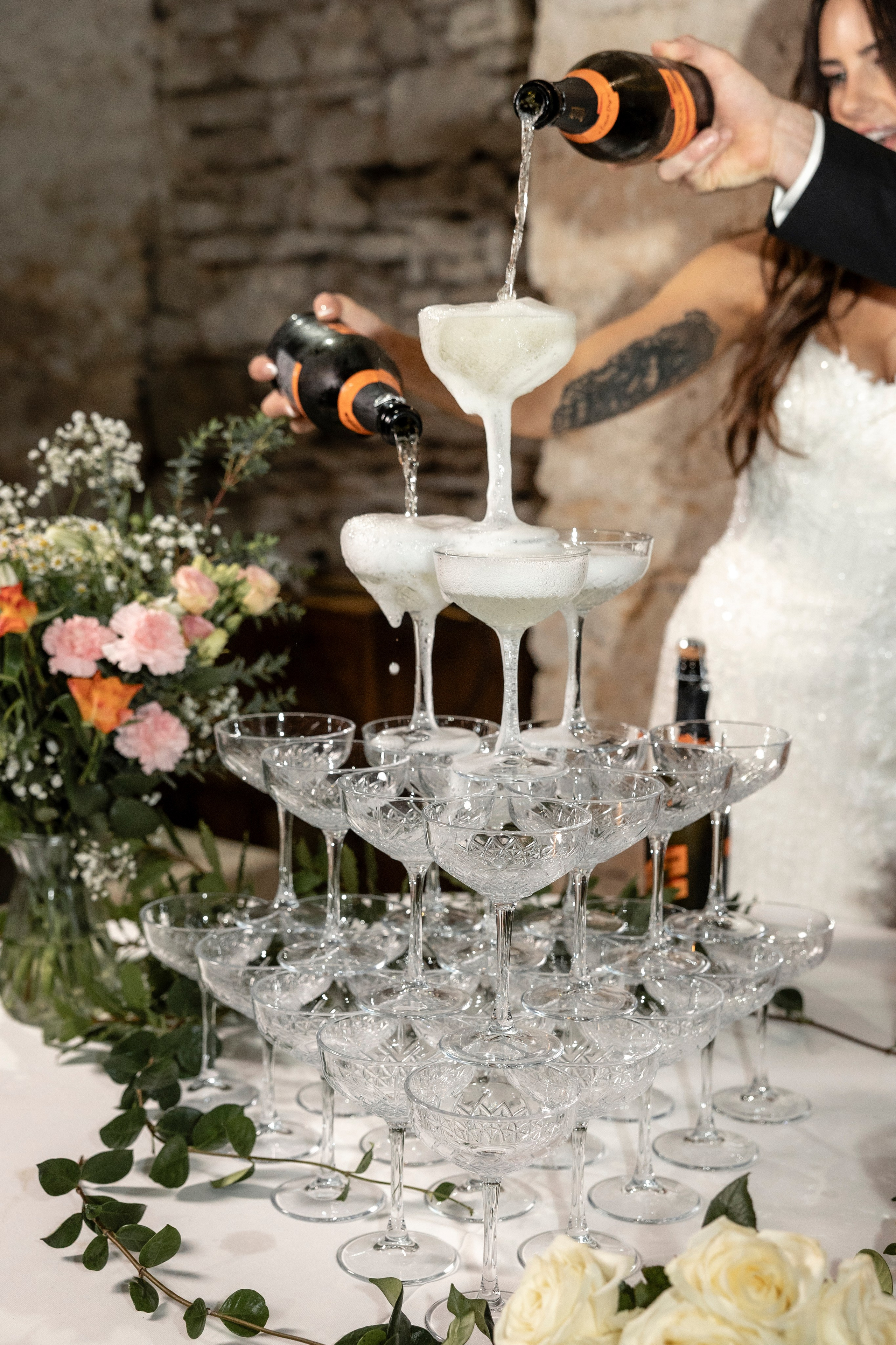 Bride and groom pouring champagne over tower during French château wedding.