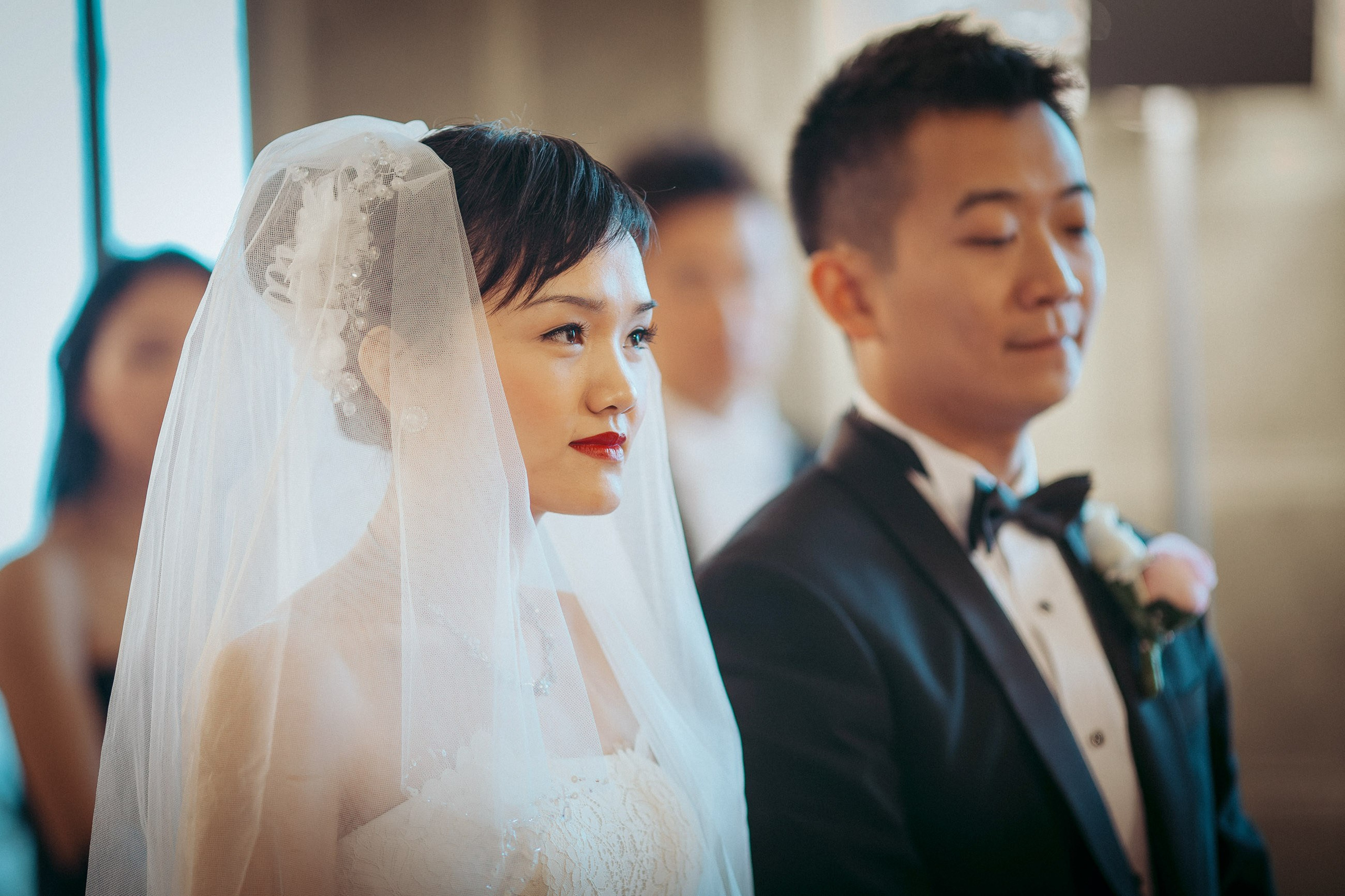 The bride and groom from Hong Kong listen intently to the officiant during their candlelit wedding ceremony at the State Chateau of Hluboka during their destination wedding in Czechia.