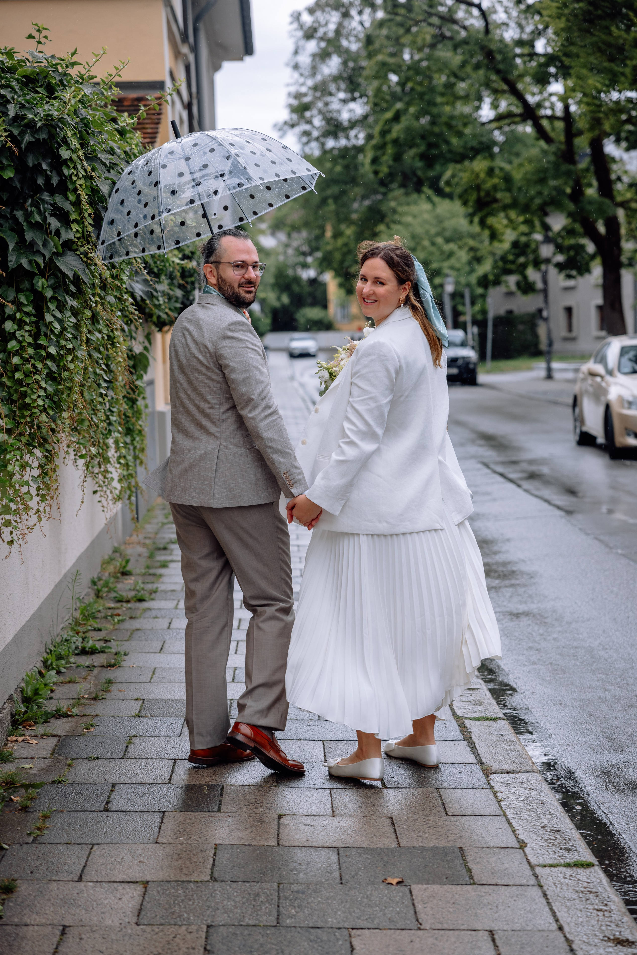 Braut und Bräutigam gehen Hand in Hand im Regen