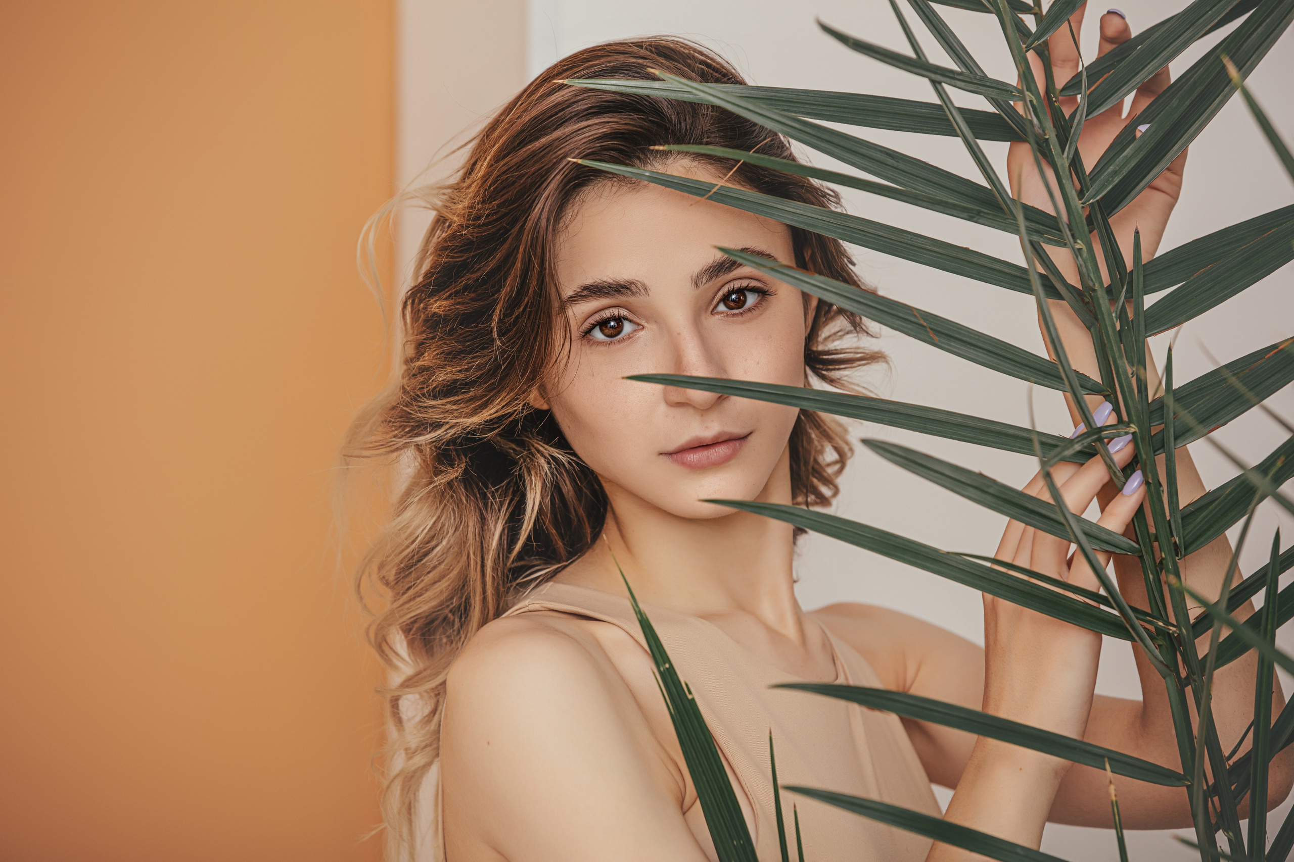 Photographe portrait à Auxerre – femme expressive sur fond jaune avec feuille tropicale