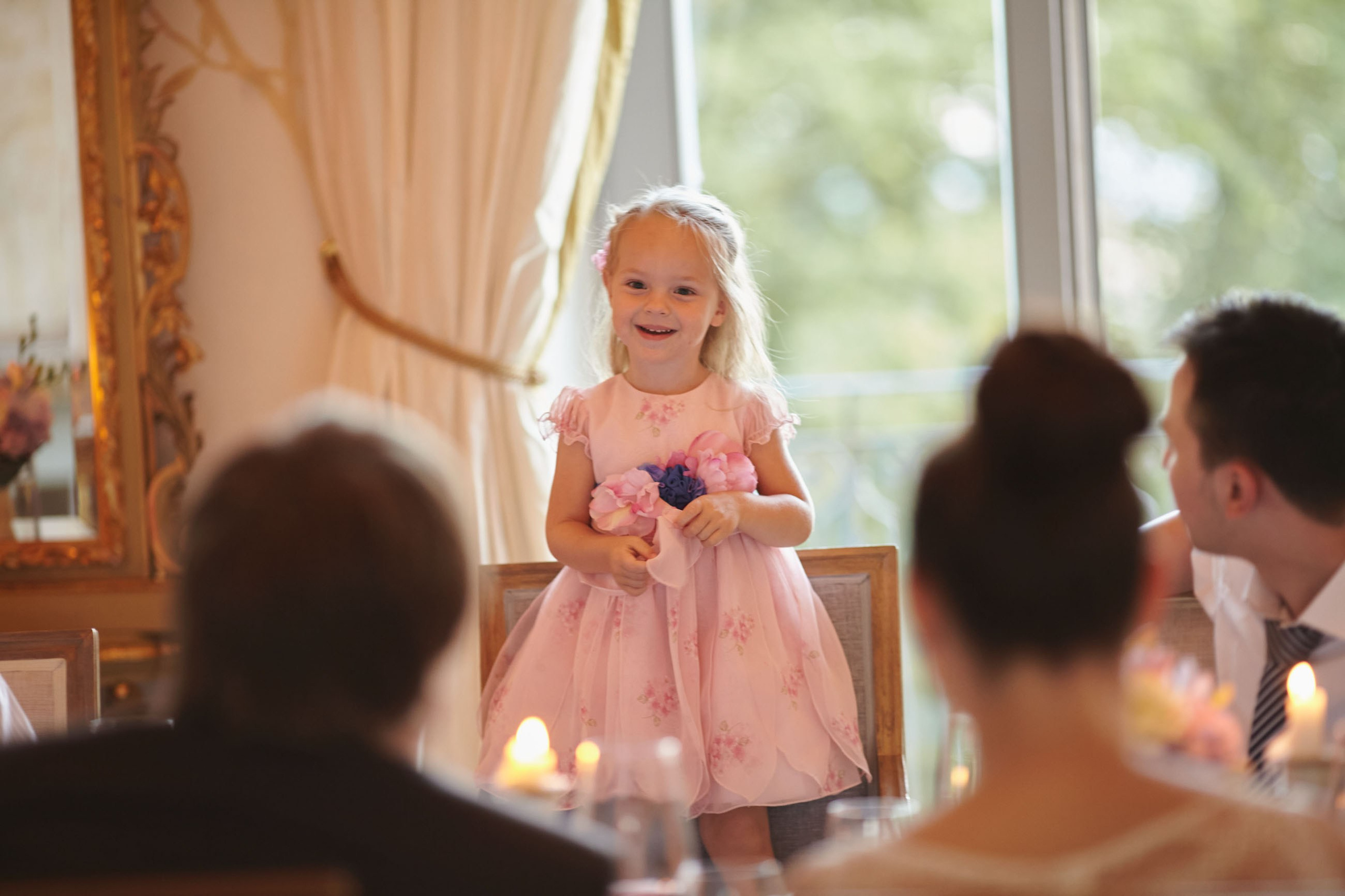 Newlyweds and guests watch as the young flower girl standing on her chair sings a song in their honor during their wedding dinner at the Chateau Mcely.
