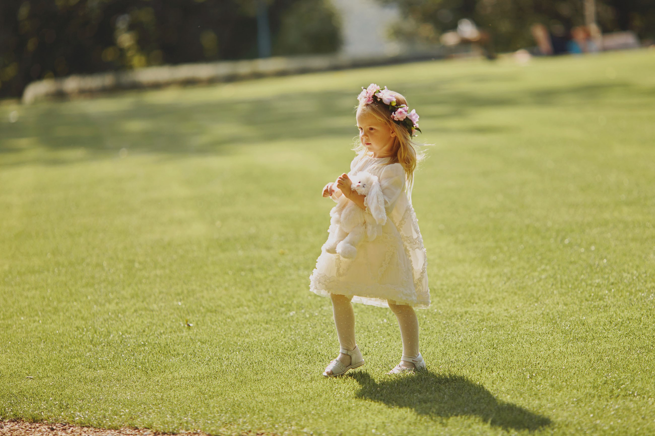 Flower girl with floral headpiece and stuffed toy running to position at chateau wedding.
