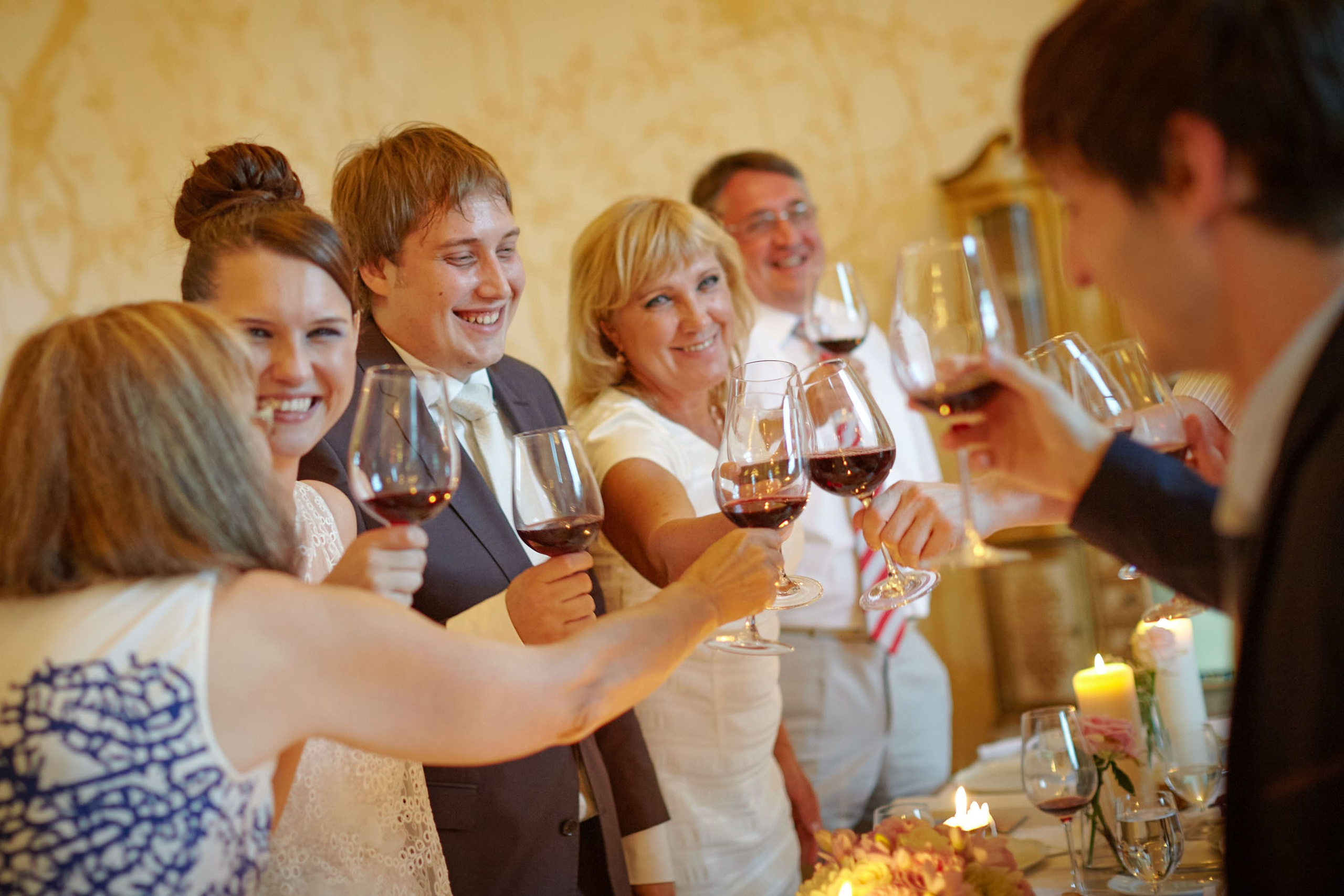 The smiling newlyweds clinked red wine glasses with family and friends during their wedding dinner at the Chateau Mcely.