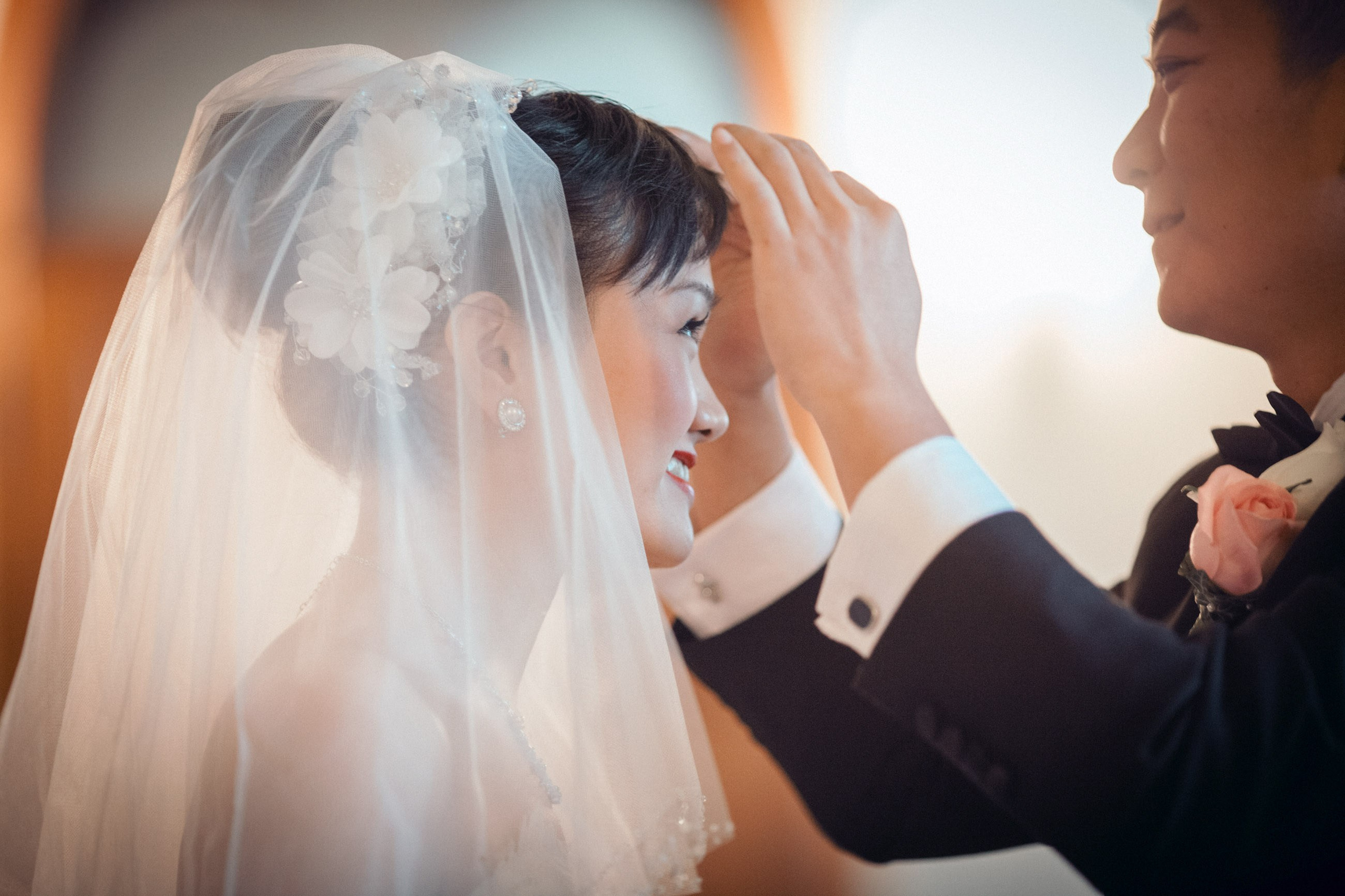 The Hong Kong groom adjusts the hair of his bride after removing her veil during their candlelit castle wedding at the State Chateau of Hluboka in Bohemia.