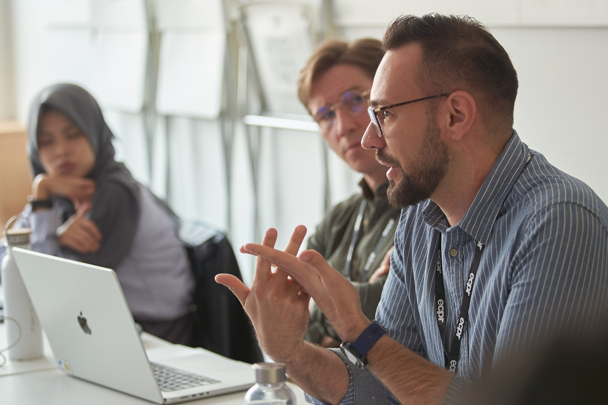 Workshop participants discuss a peer’s paper presentation in a Charles University seminar room.