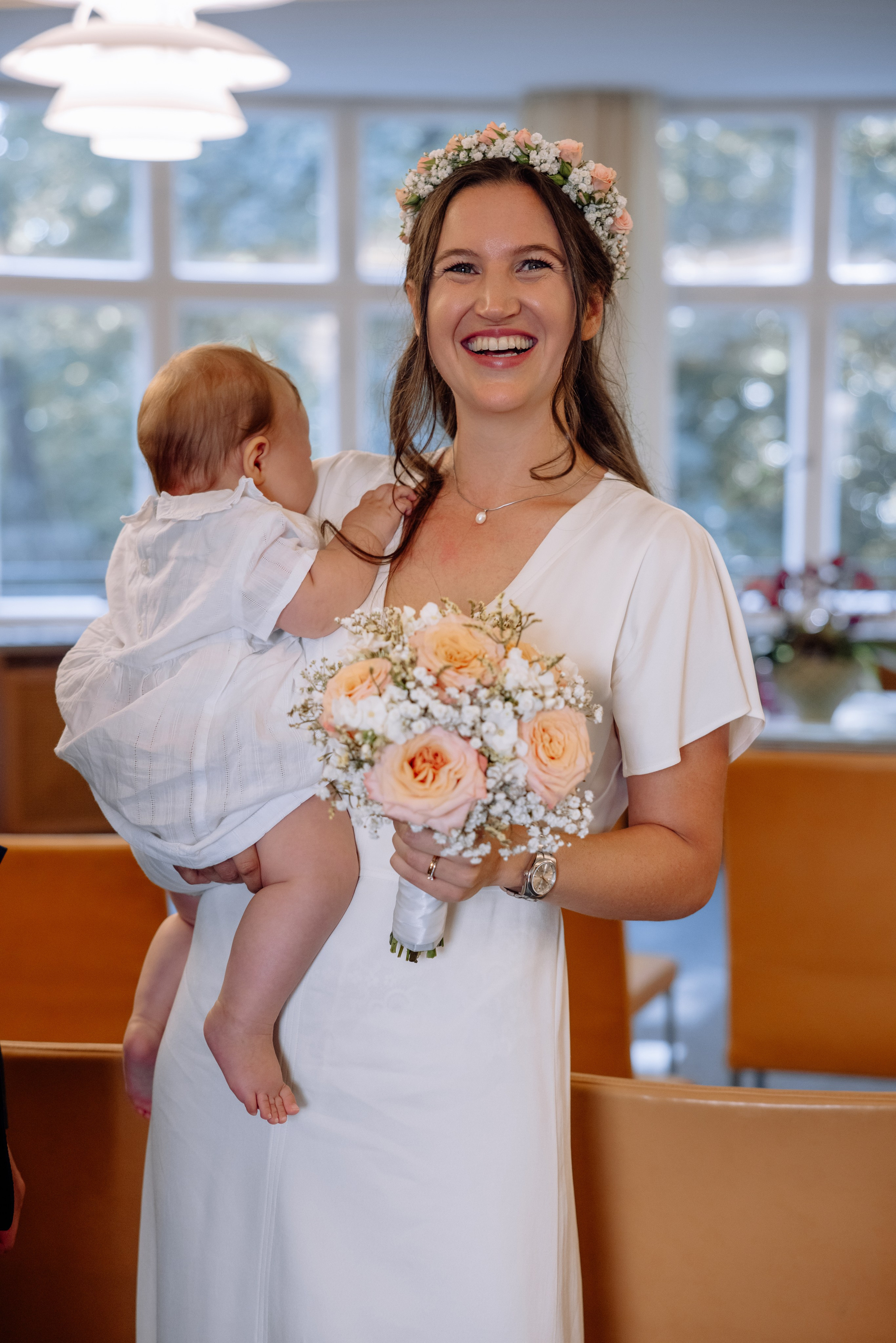 Braut hält Baby sanft – glücklicher Moment beim Verlassen des Standesamts Mandlstraße 14