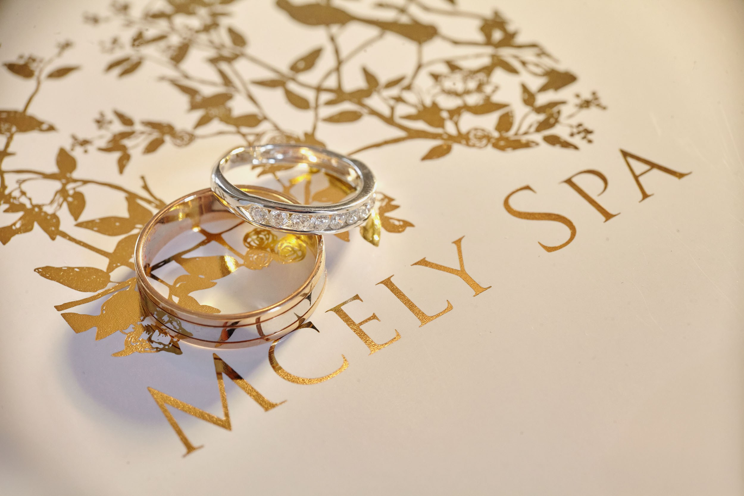 Designer wedding rings displayed on a gold-embossed Mcely Spa catalog in the luxurious bridal suite.