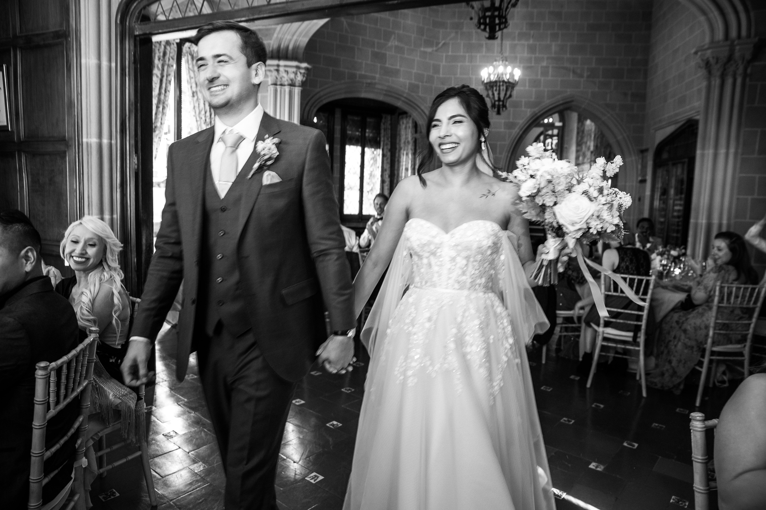The bride and groom entering the wedding reception are greeted by all the guests.