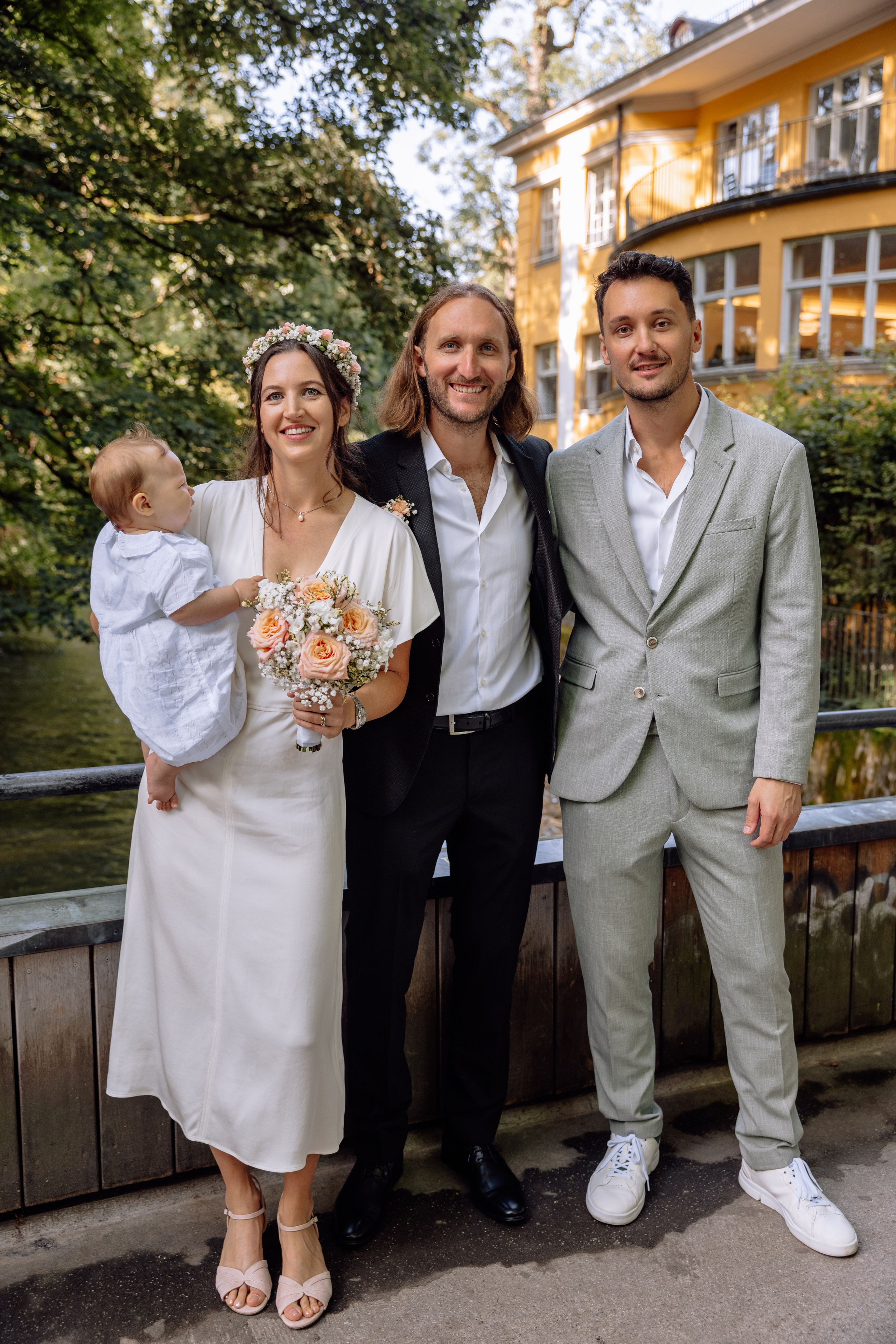 Braut und Bräutigam interagieren mit Gästen – Standesamt Schwabing im Hintergrund