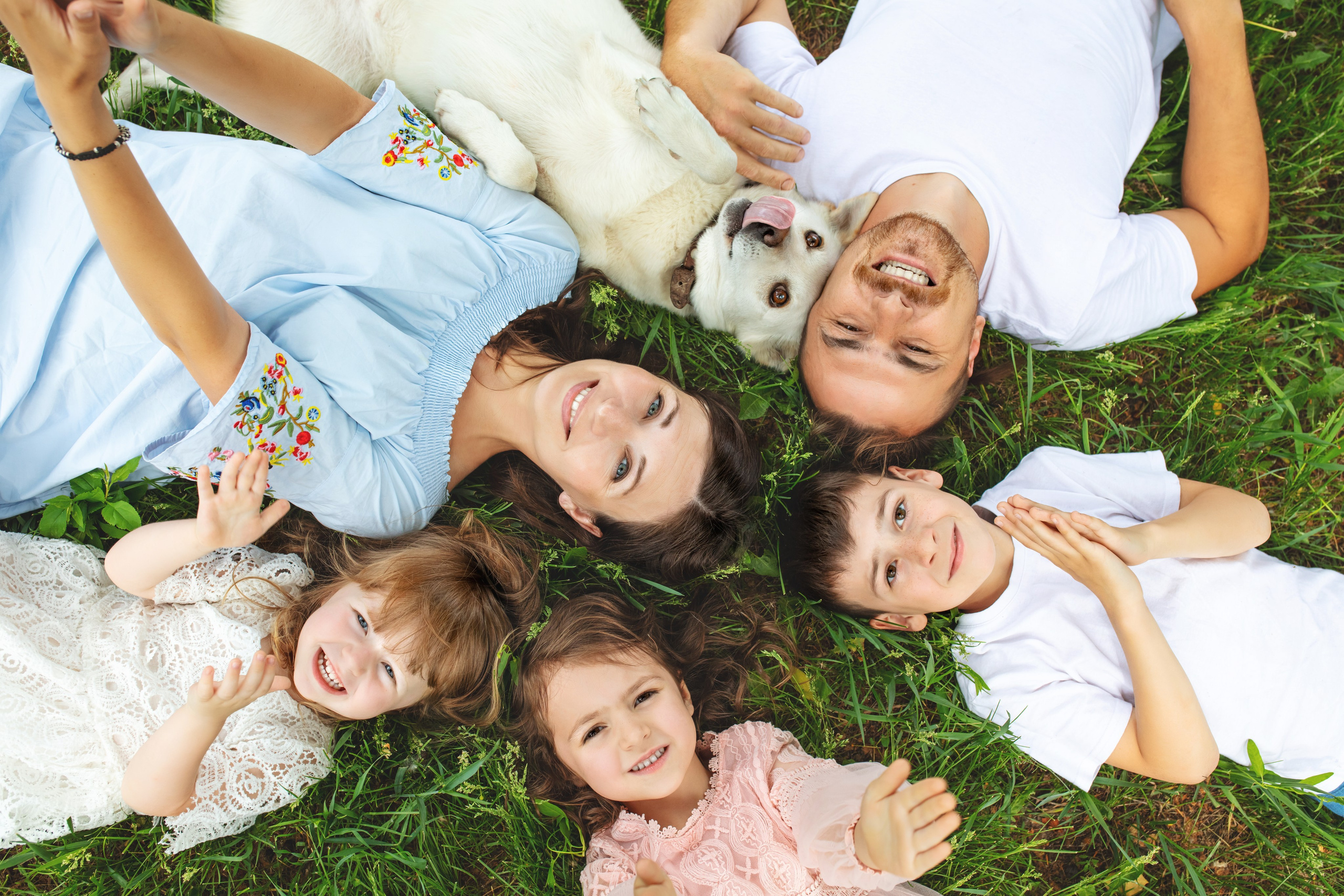 Portrait familial joyeux allongé dans l'herbe, séance photo naturelle en extérieur