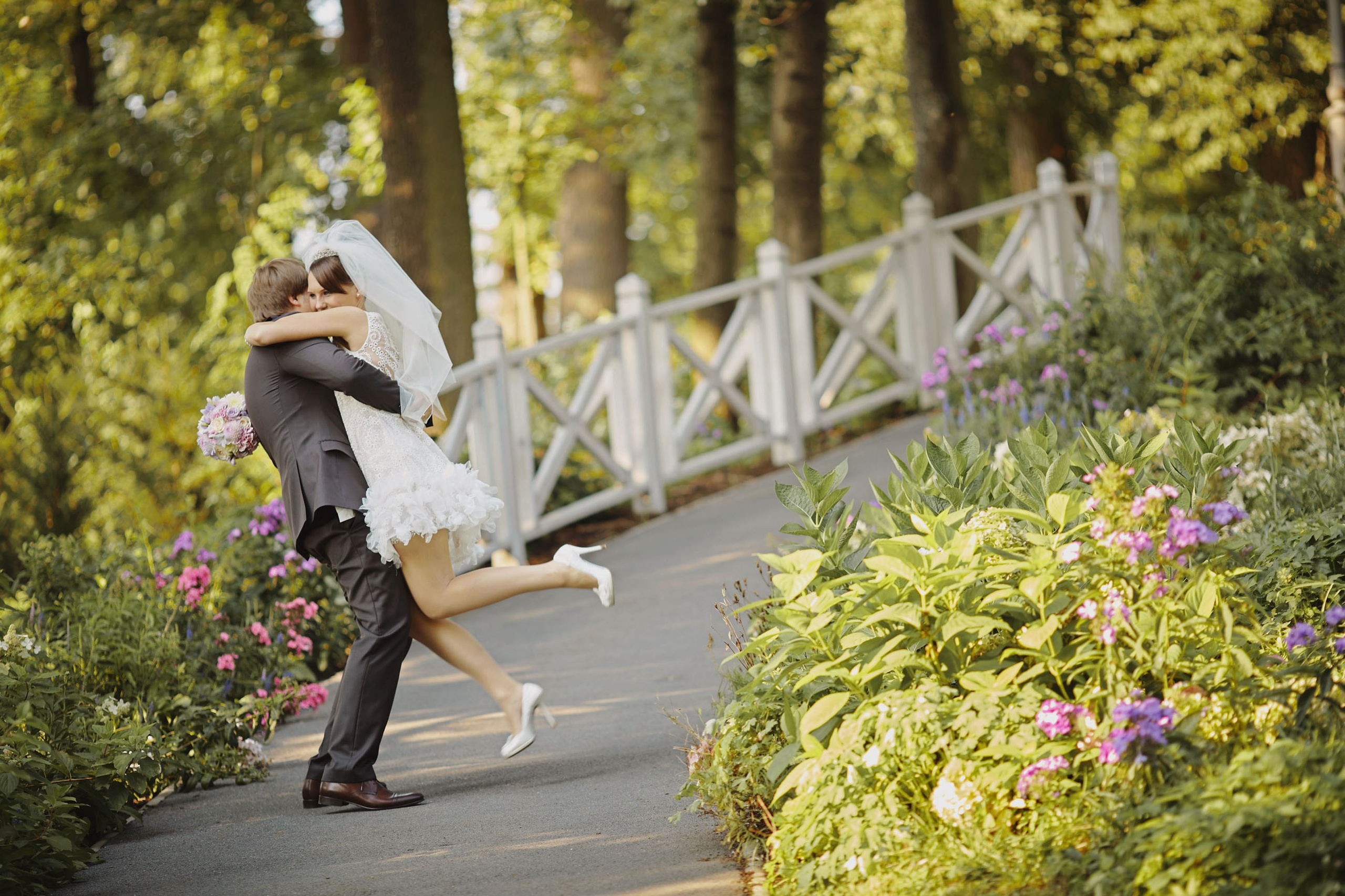 A groom joyfully spins his bride amidst the vibrant garden landscapes of Chateau Mcely, celebrating their magical wedding ceremony.