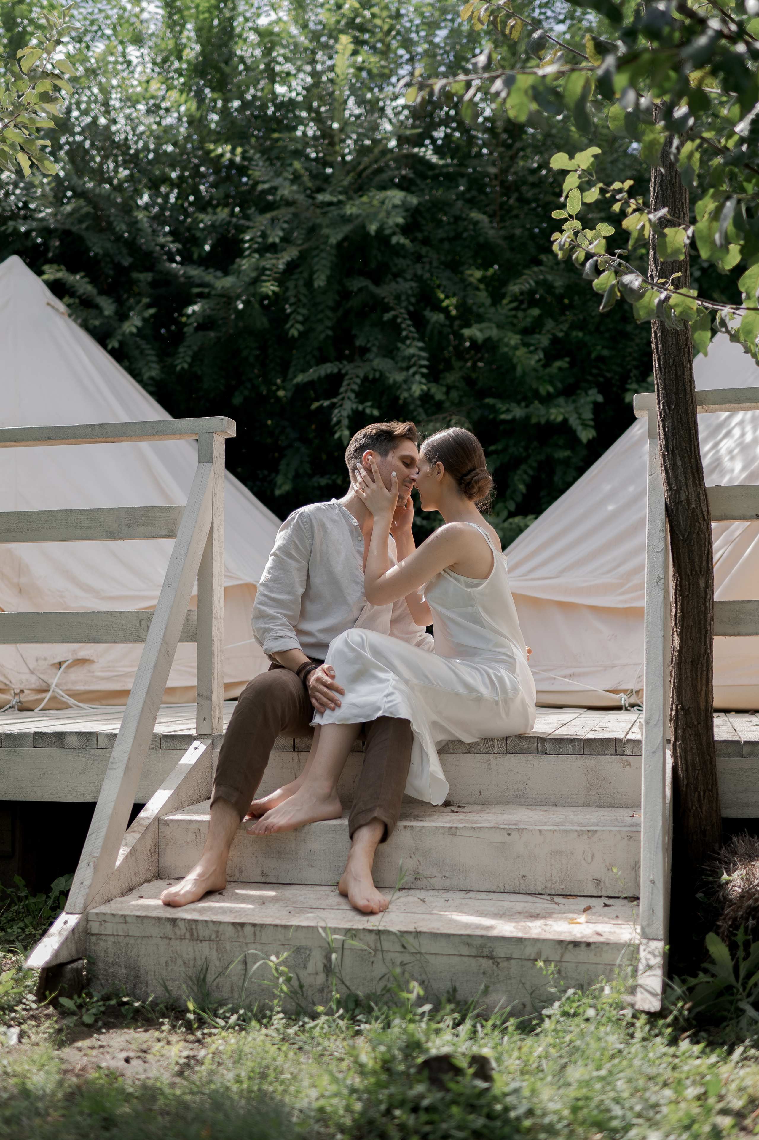 The couple's wedding morning is embraced in a secluded garden setting, where cozy glamping tents provide an intimate haven for their loving and tender moments.
