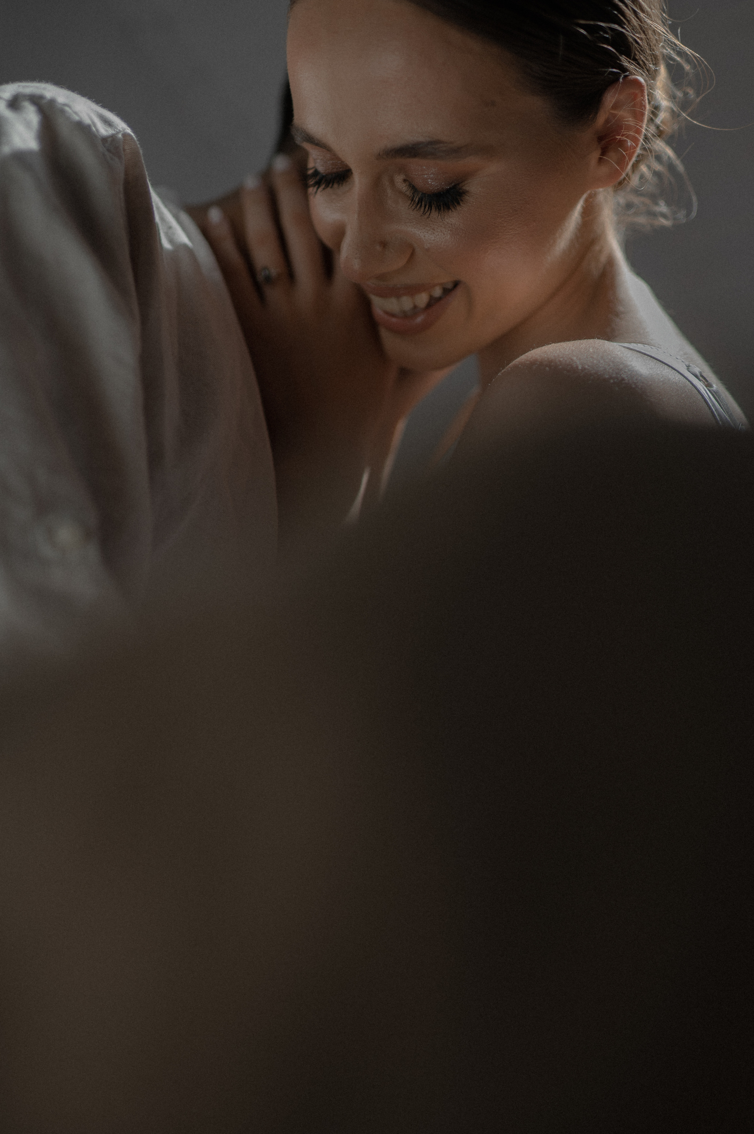 Capturing the essence of joy, the couple shares laughter while kissing in a beautifully composed photograph, their unique engagement ring with a stunning stone shining brightly.