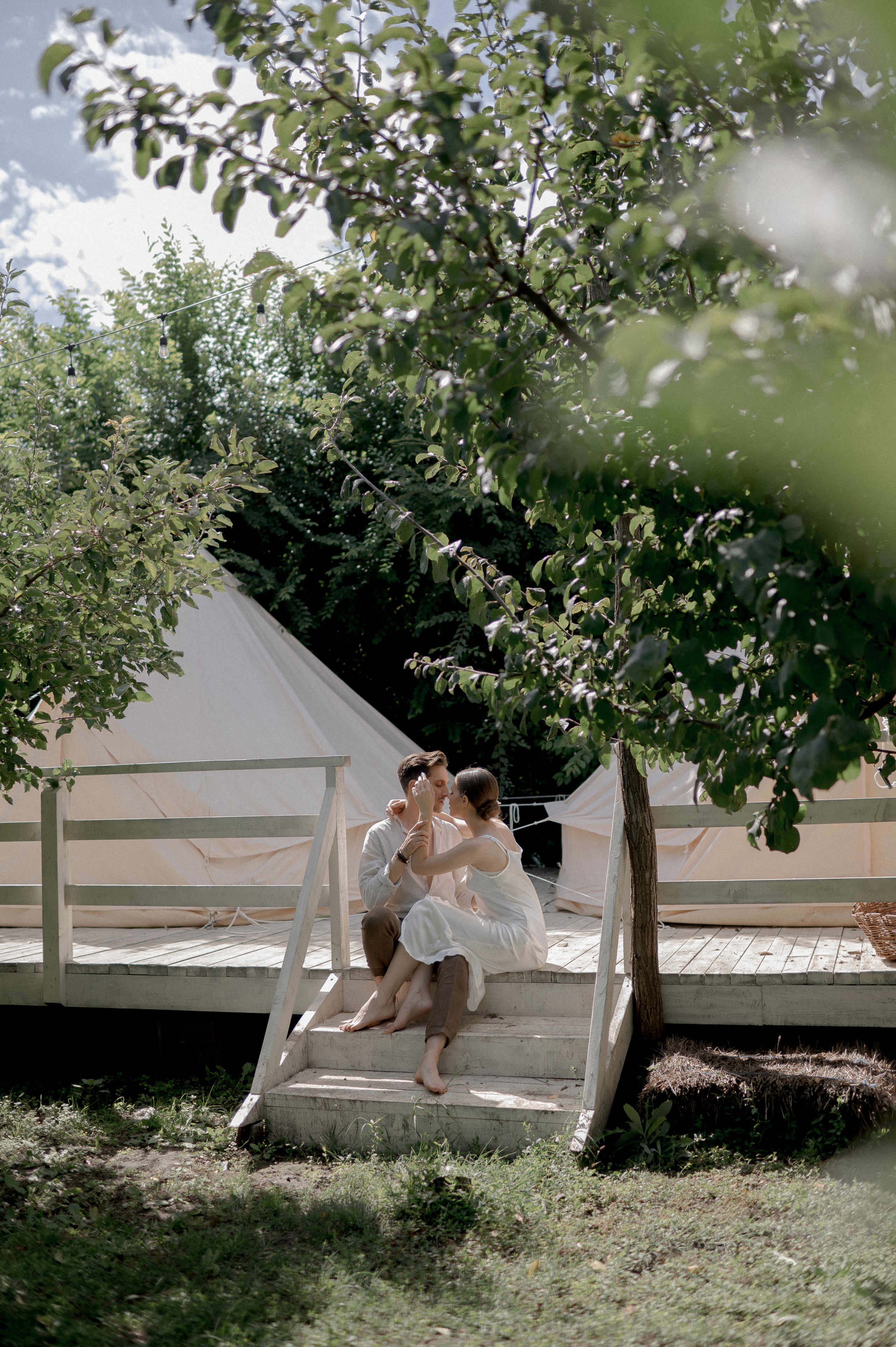 The couple's wedding morning is enveloped in the seclusion of a lush garden, where glamping tents provide an intimate space for their loving gestures and tender exchanges.