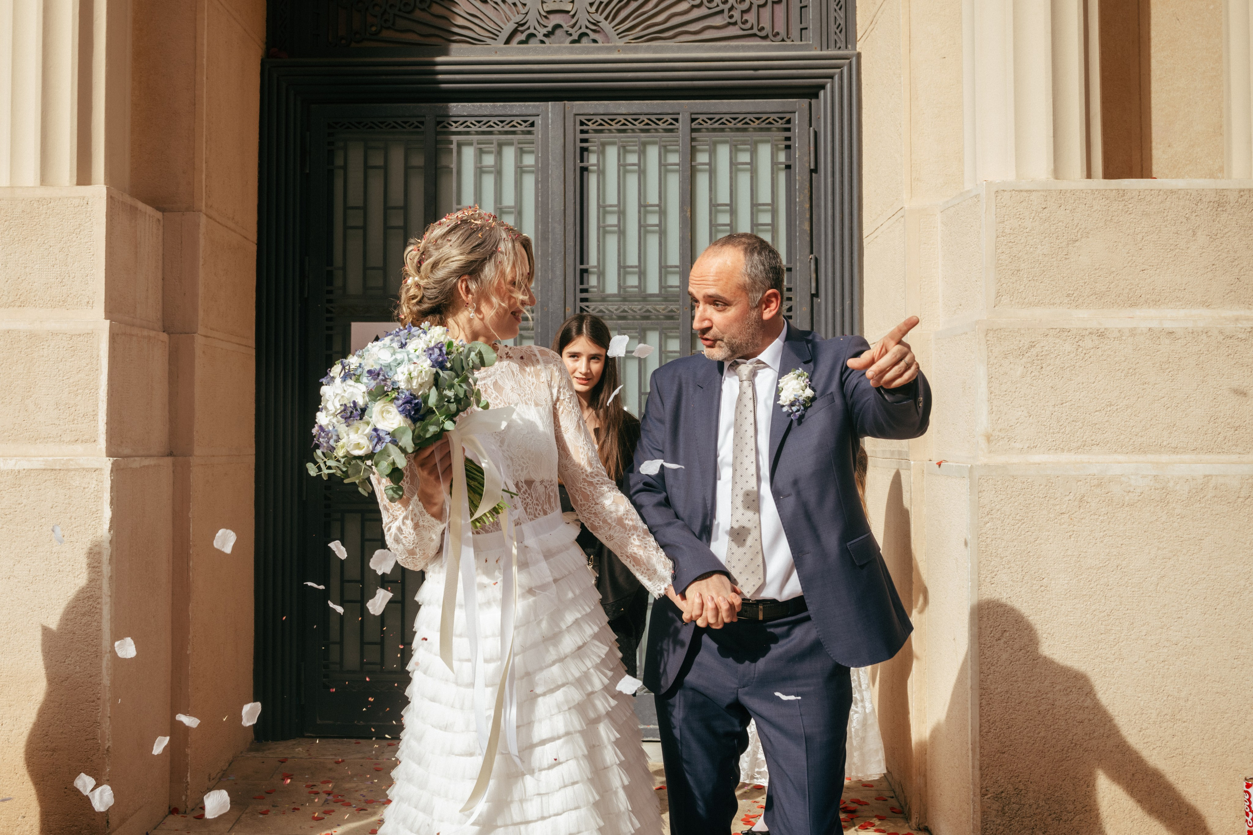 Молодожёны выходят из мэрии, а гости осыпают их конфетти.