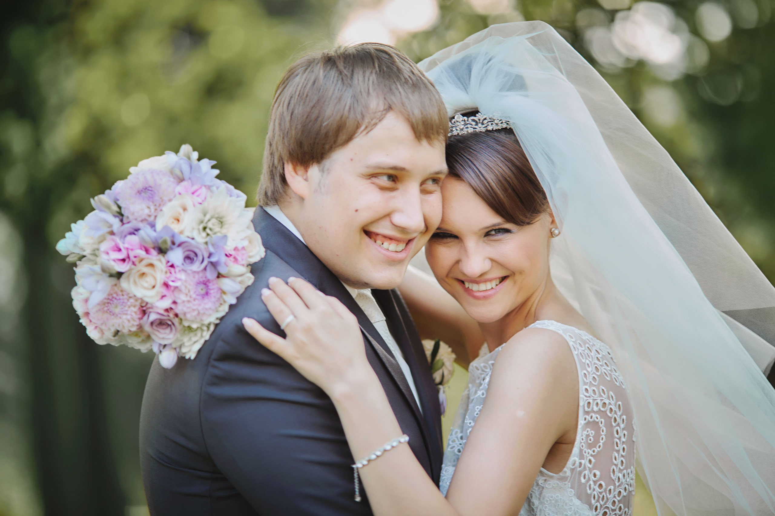 Bride and groom share a laugh as they hug each other tight on the grounds of a stately chateau.