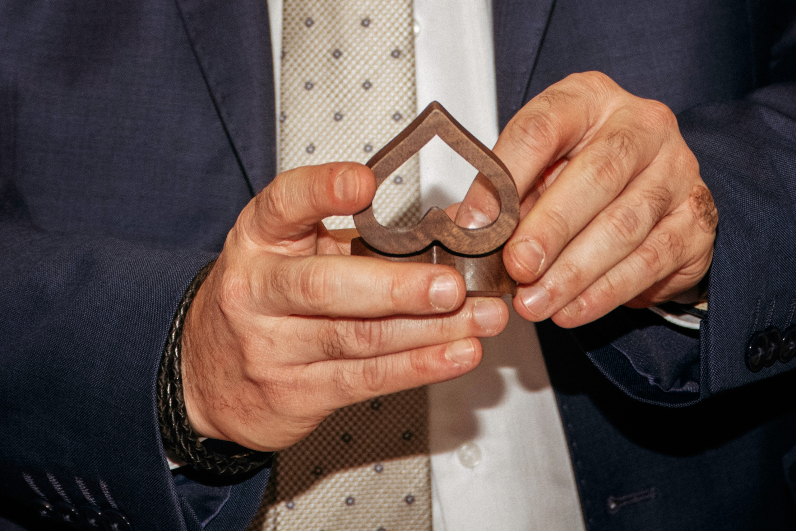 Руки жениха достают обручальное кольцо из коробки в форме сердца.