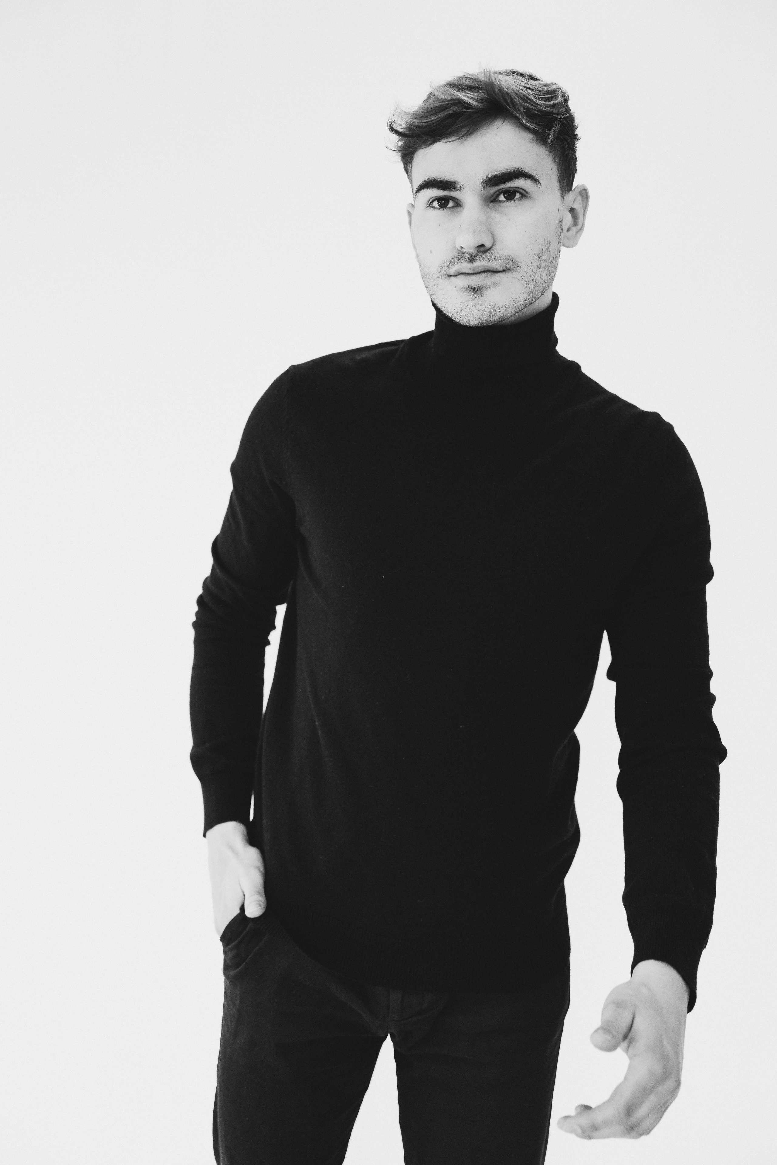 Full-length studio image of male model in fitted black clothing for a modeling portfolio shoot.