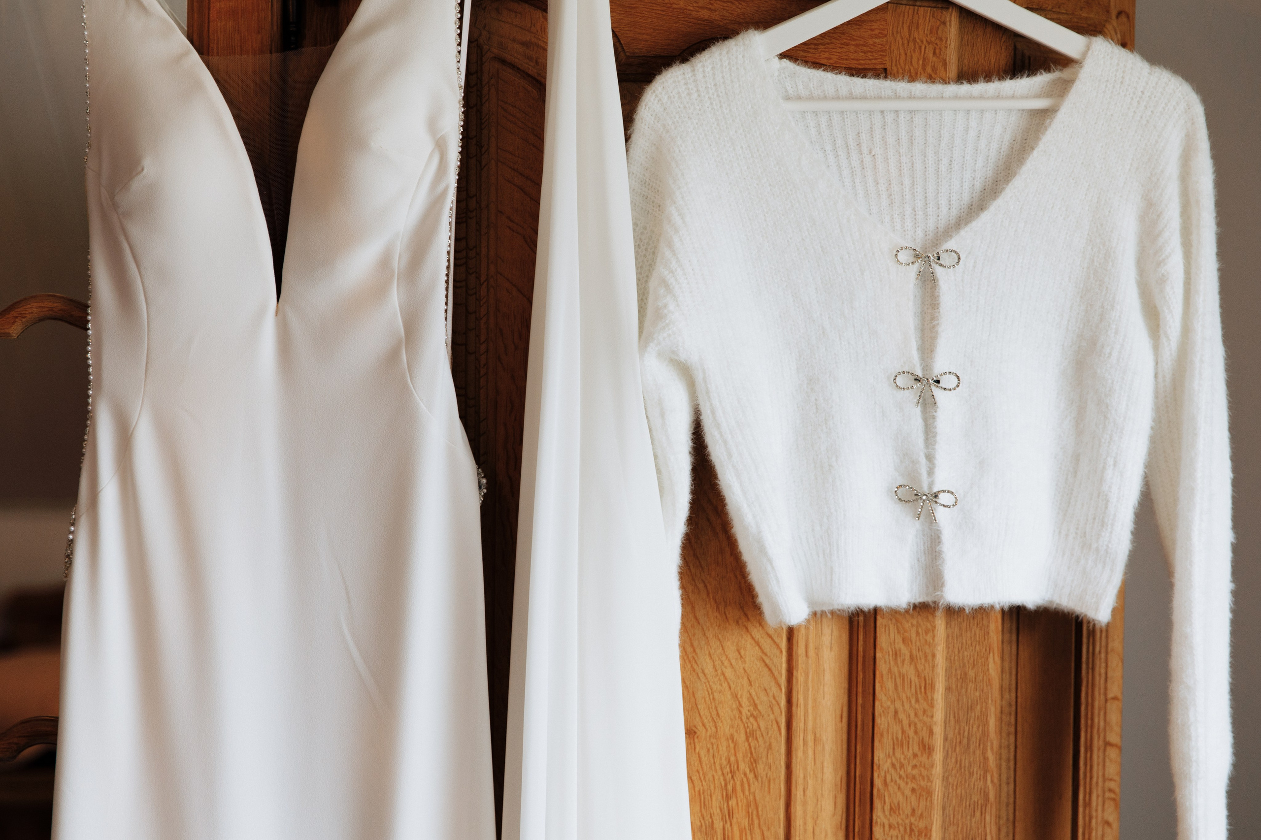 Elegantes Hochzeitskleid und leichte Jacke hängen an einem Kleiderschrank