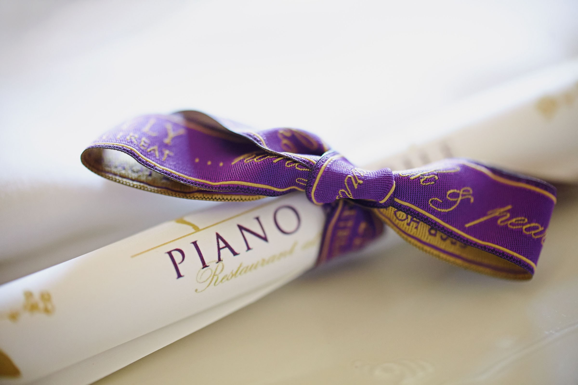 Restaurant menu elegantly rolled and tied with a purple ribbon.