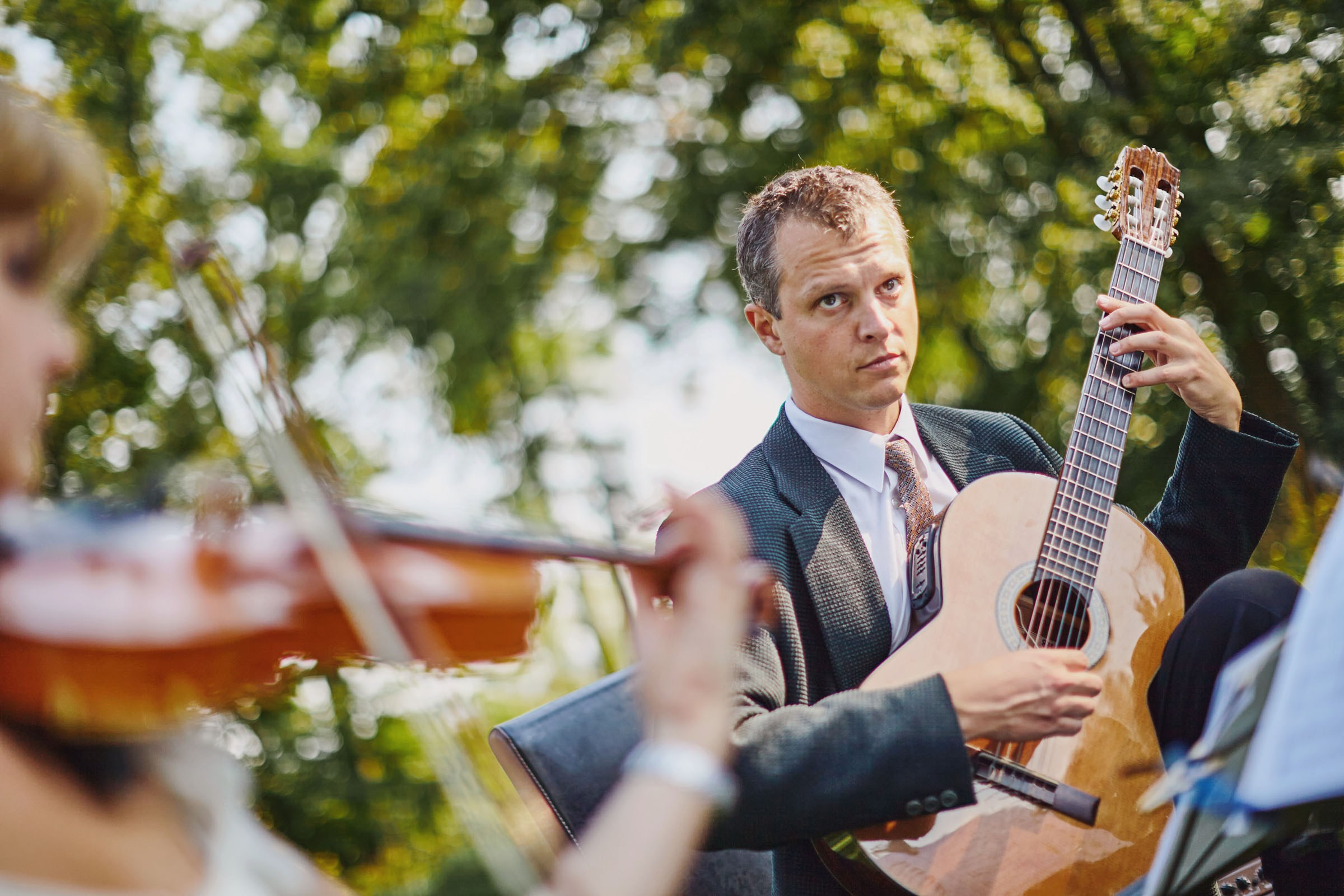A guitarist performs in a trio on the grounds of a historic chateau.