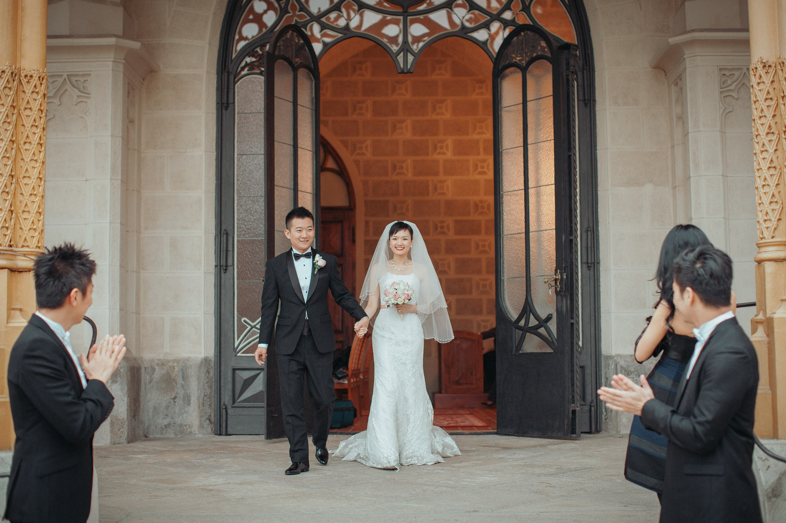 The Hong Kong bride and groom are met with a round of applause as they exit the ceremonial hall during their destination castle wedding at Hluboka in the Czech Republic.