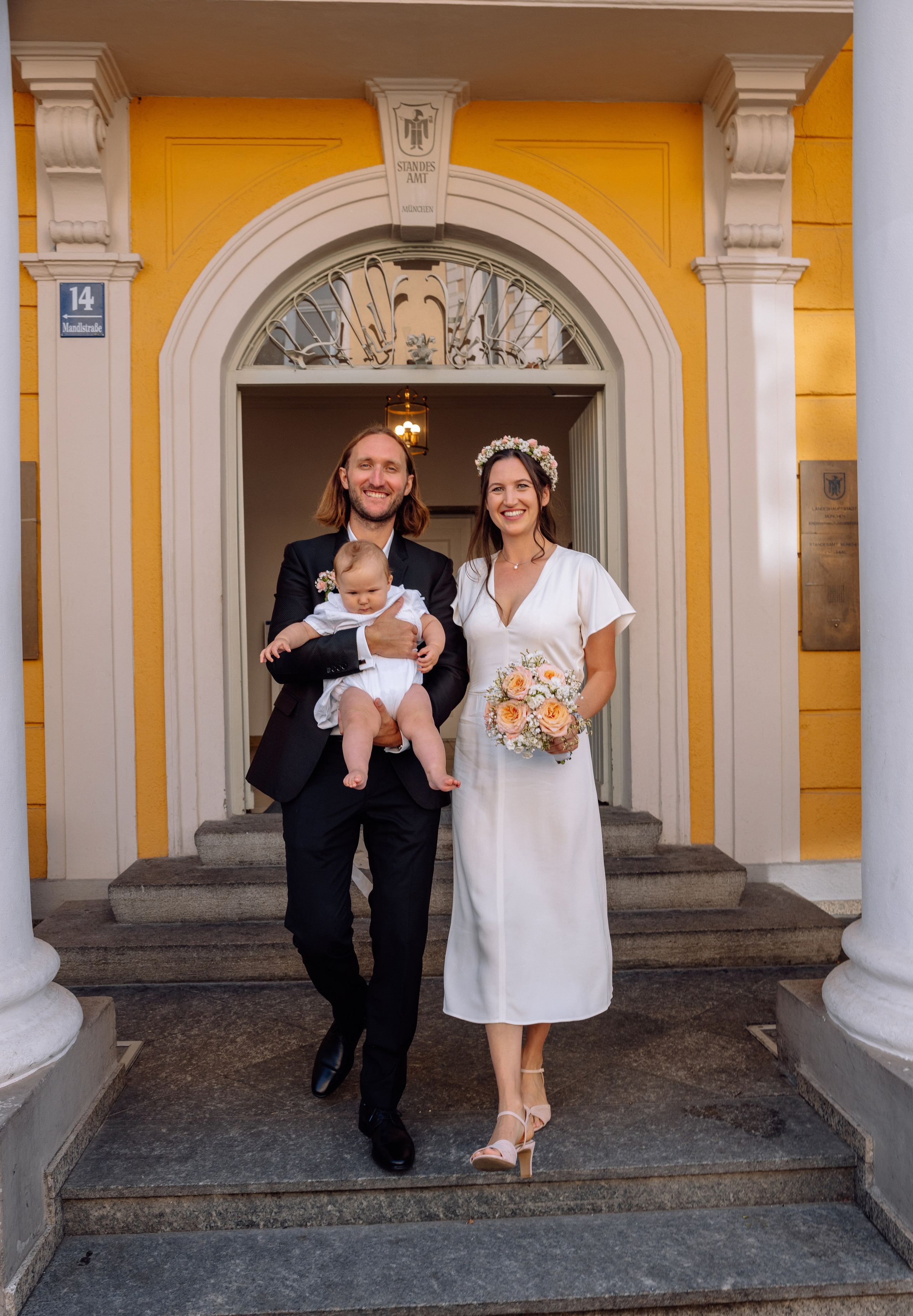 Baby in den Armen der Eltern – Treppenabgang aus Standesamt Mandlstraße 14.