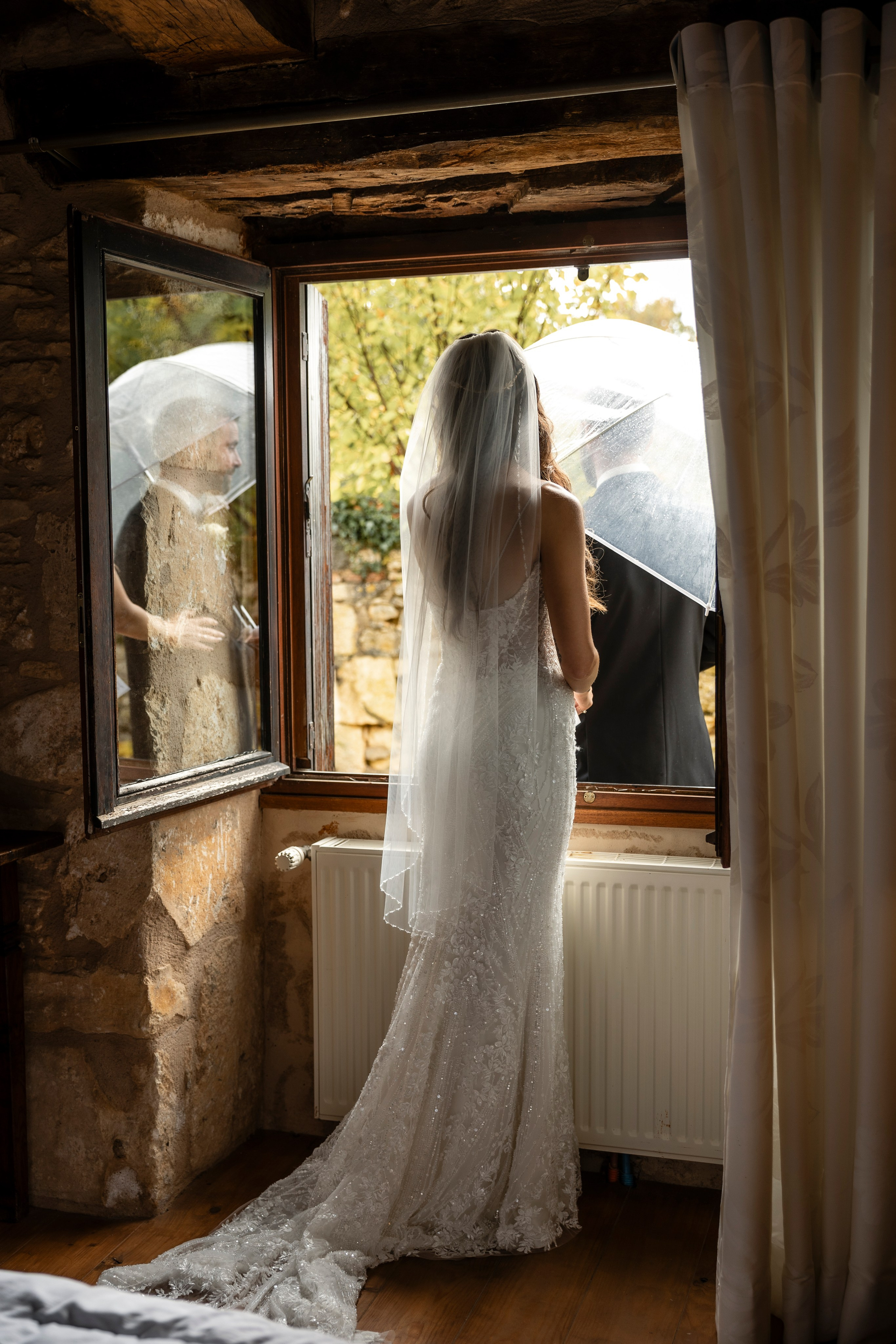 Groom standing under umbrella during rainy wedding in Dordogne, France.