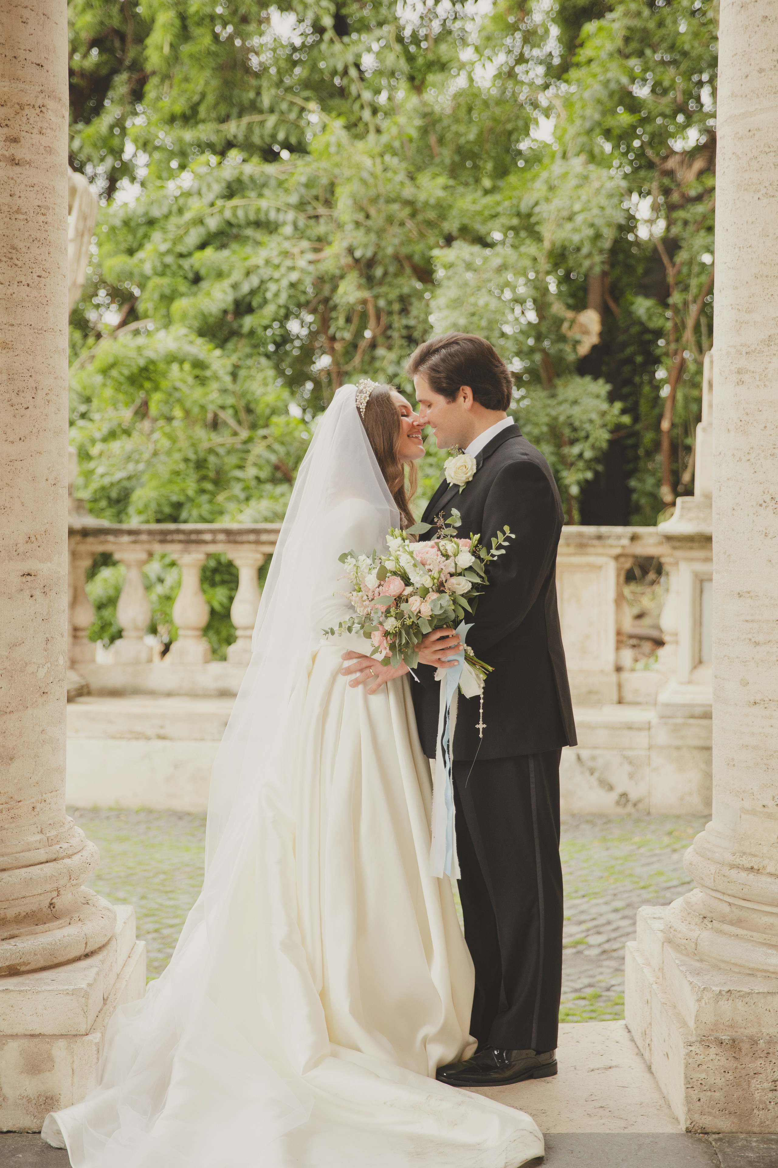 Newly married couple kissing in the arcades of Piazza del Campidoglio in Rome.