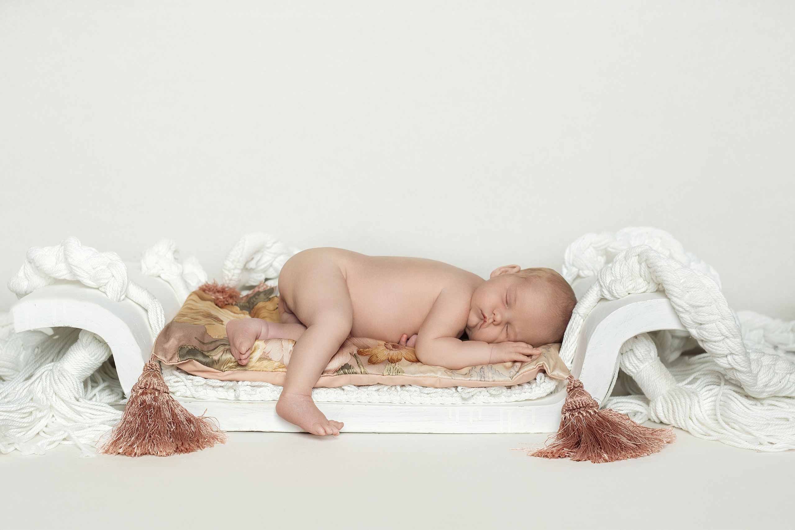 Nouveau-né dormant sur un petit lit décoratif, séance photo artistique de naissance en studio