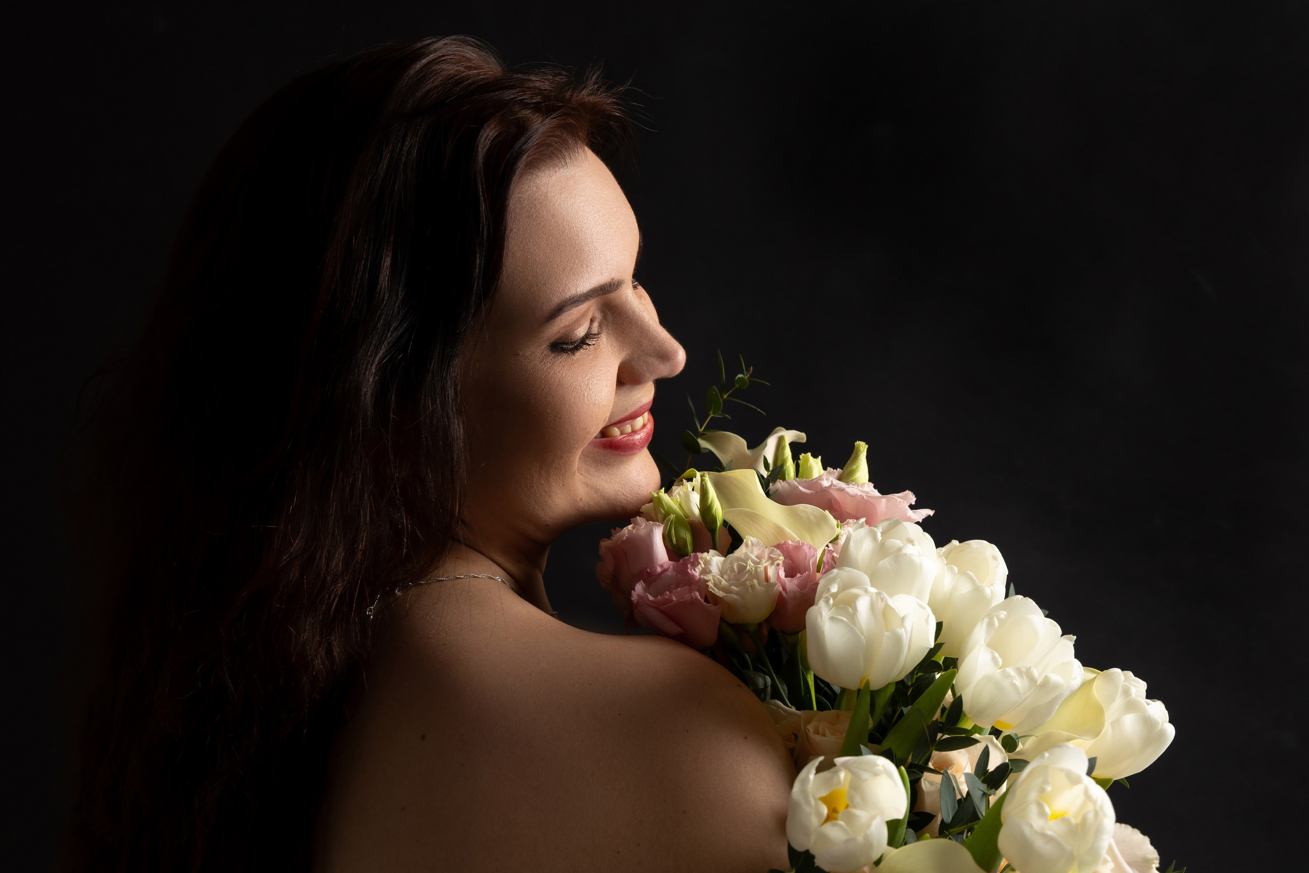 "Schwarz-Weiß-Porträt einer lächelnden Frau mit lockeren Haaren. Sanfte Schatten verleihen Tiefe."