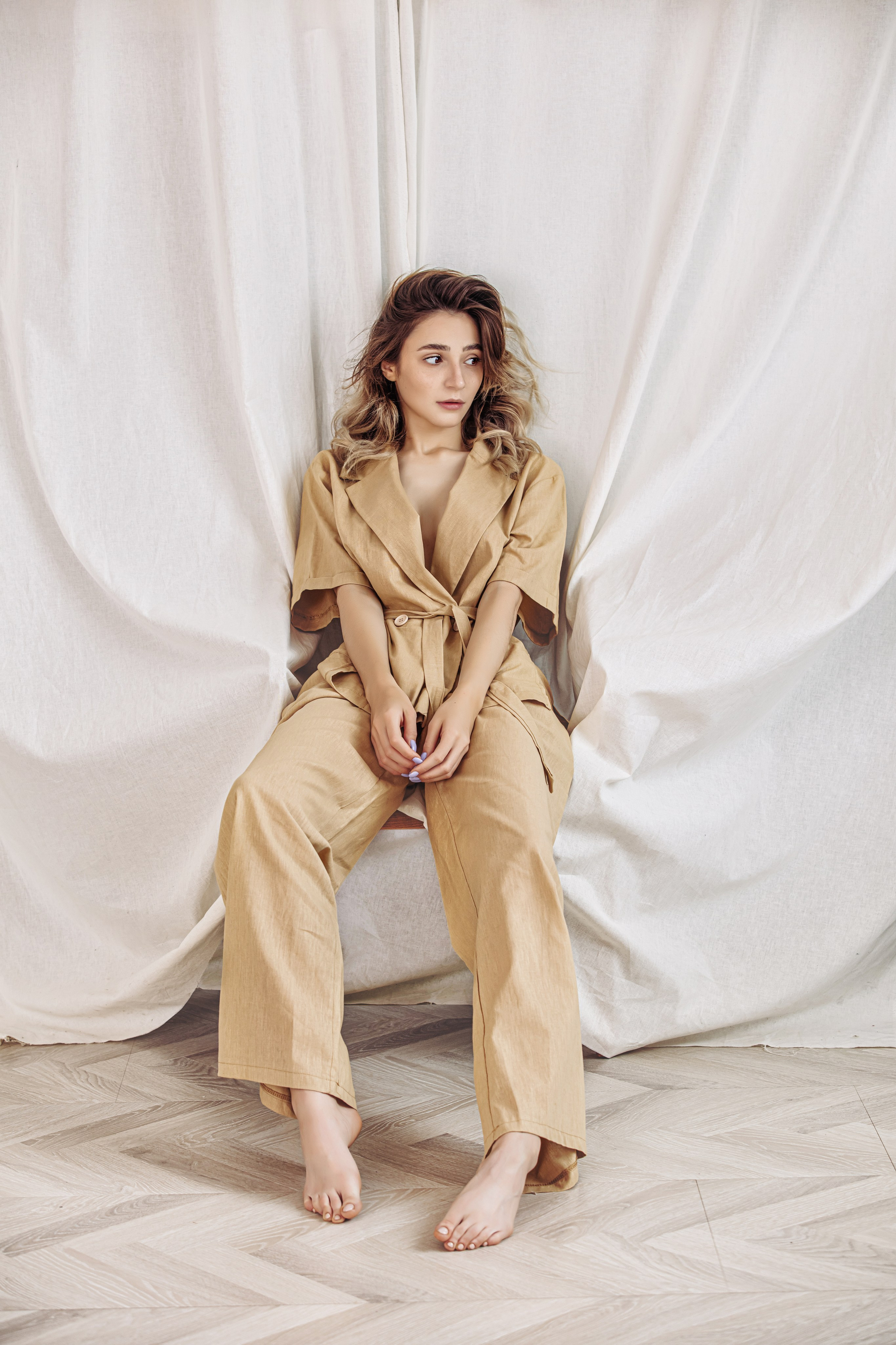 Modèle assise dans une tenue dorée – portrait professionnel en intérieur avec arrière-plan clair et stylisé