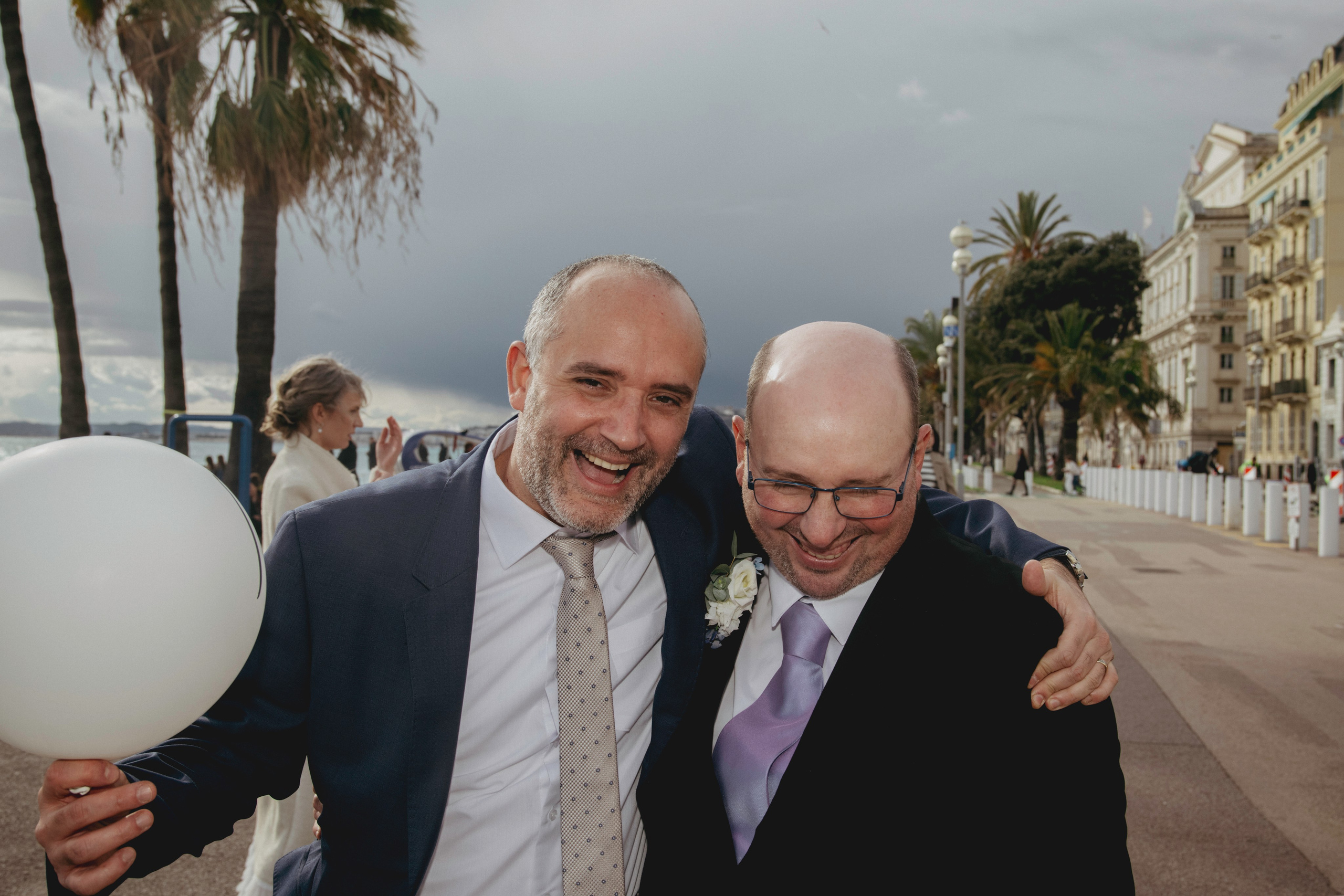 Жених с другом идёт с надувным шариком и смеётся.