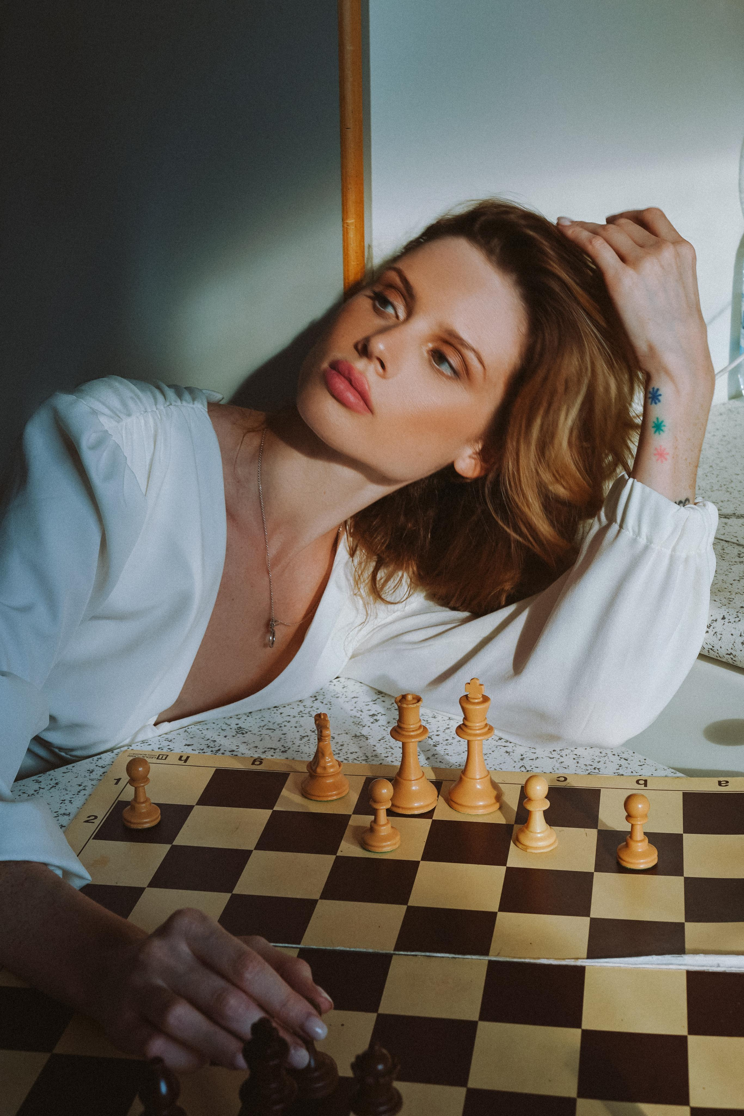 a model with bronze makeup posing in front of a chess board