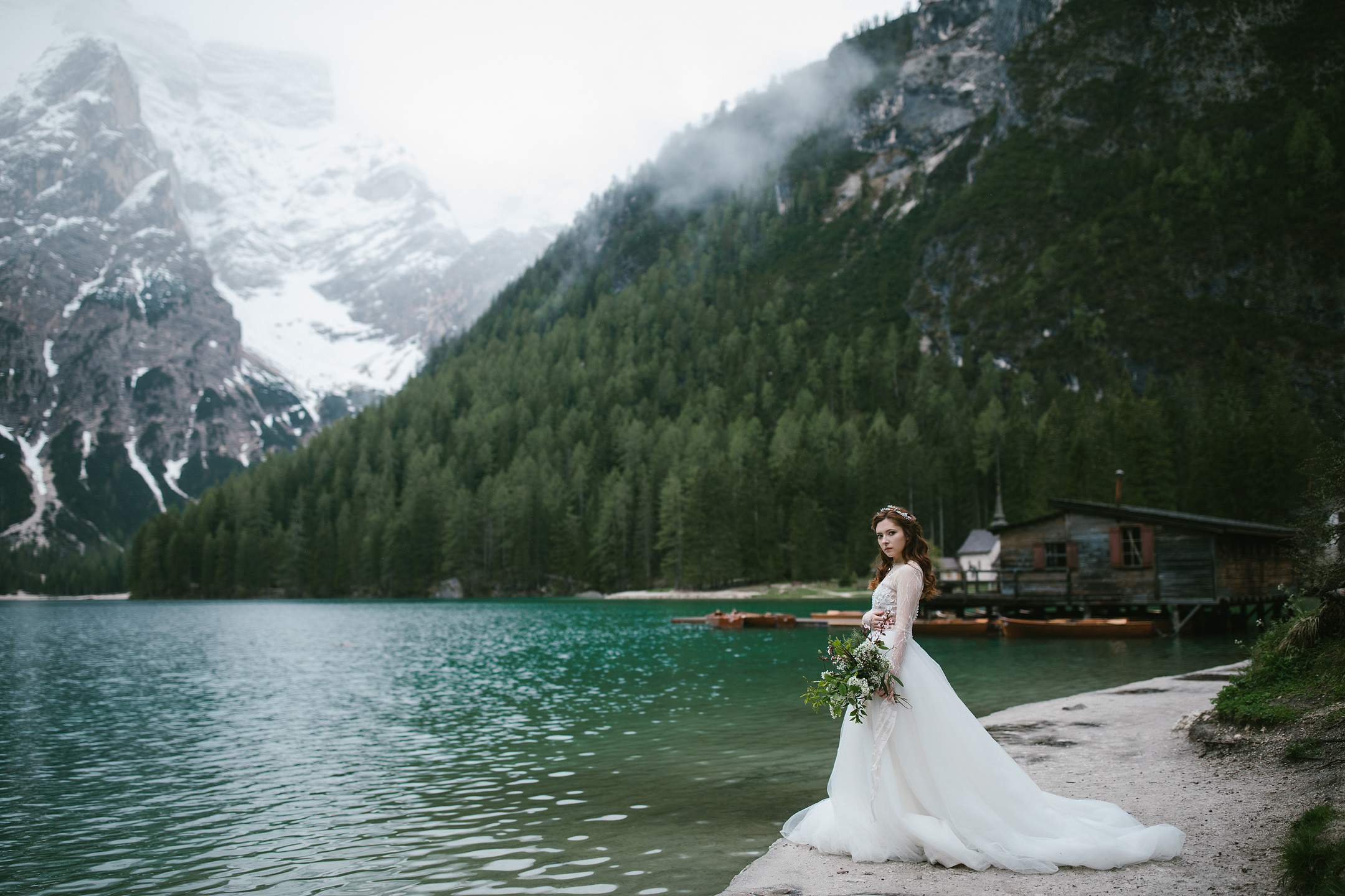 Braut am smaragdgrünen See mit Bergen im Hintergrund