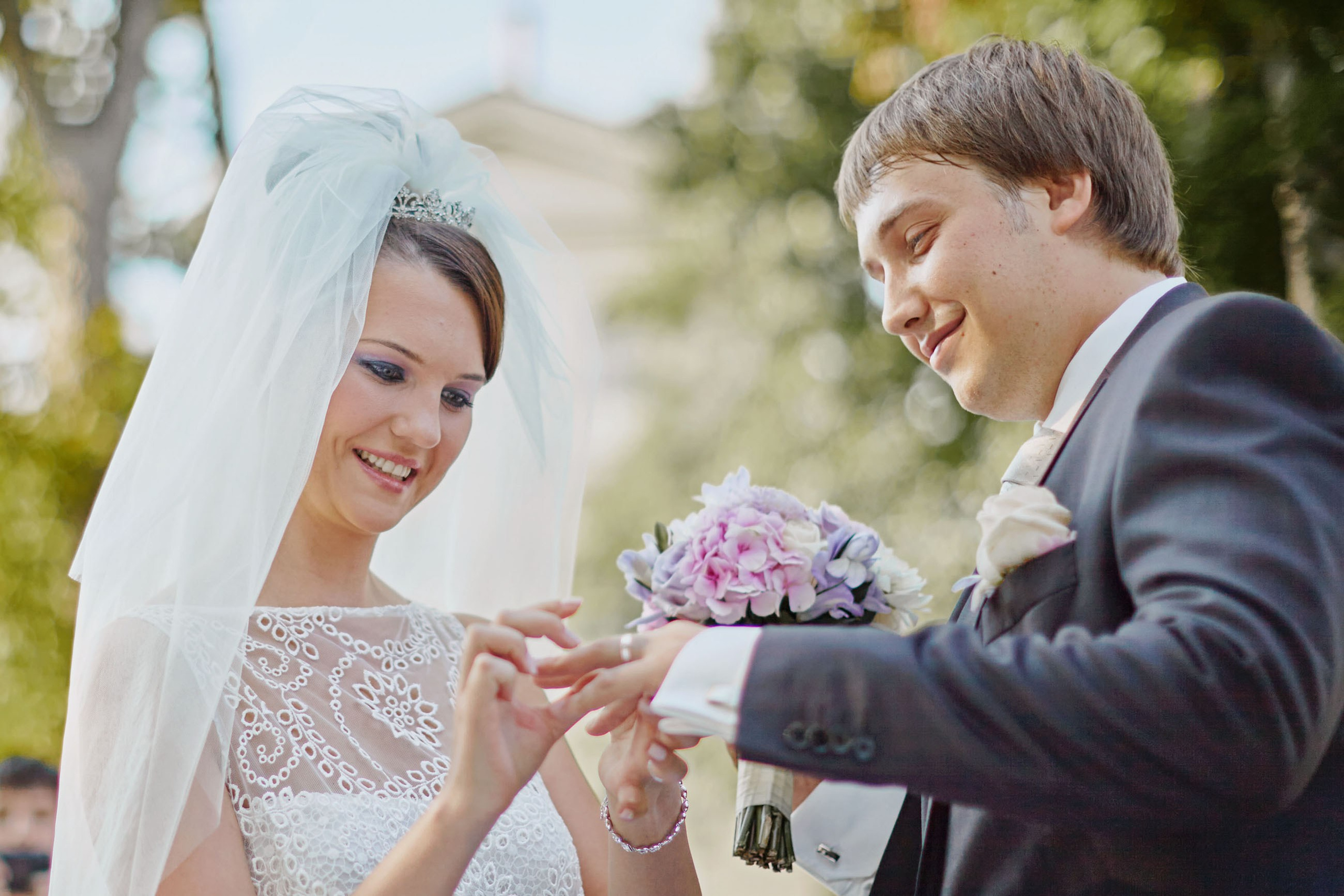 Bride placing wedding band on groom at outdoor chateau wedding in Czechia.