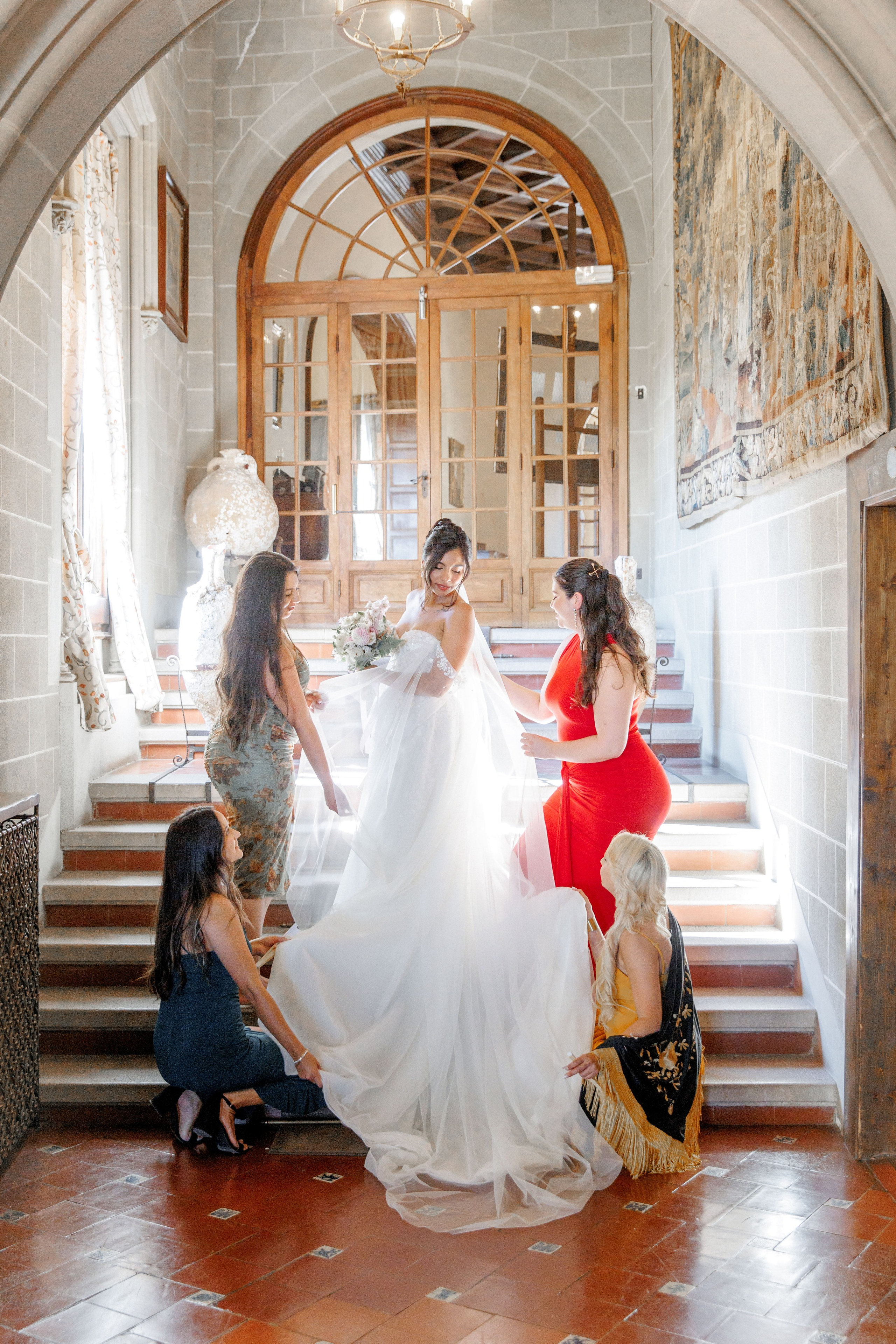 Bridal party on the stairs of a fantastic Spanish wedding venue, adjusting the wedding dress.