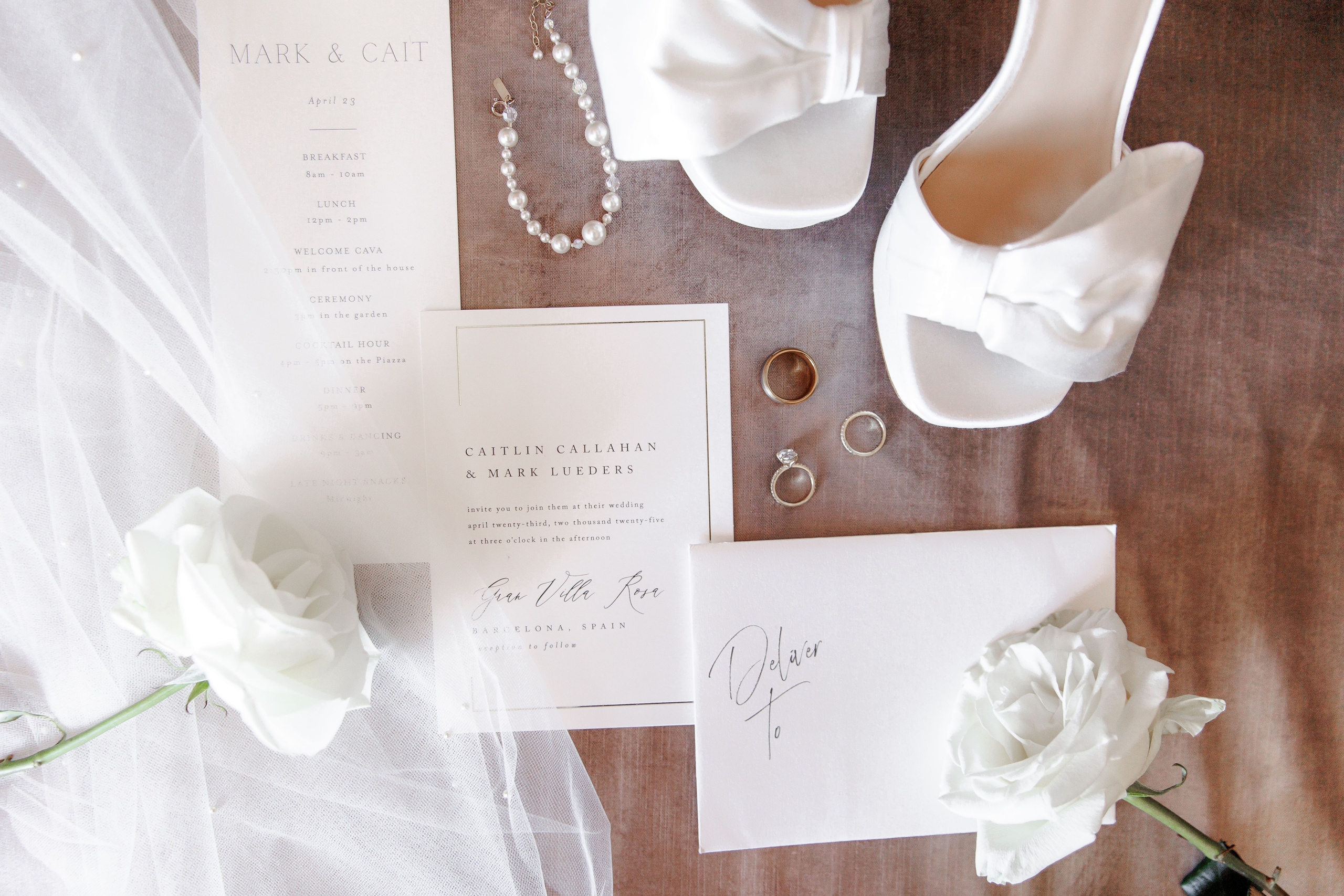 Artistic close-up of a bride's shoes and stationery featuring vibrant flowers for a destination wedding in Barcelona.