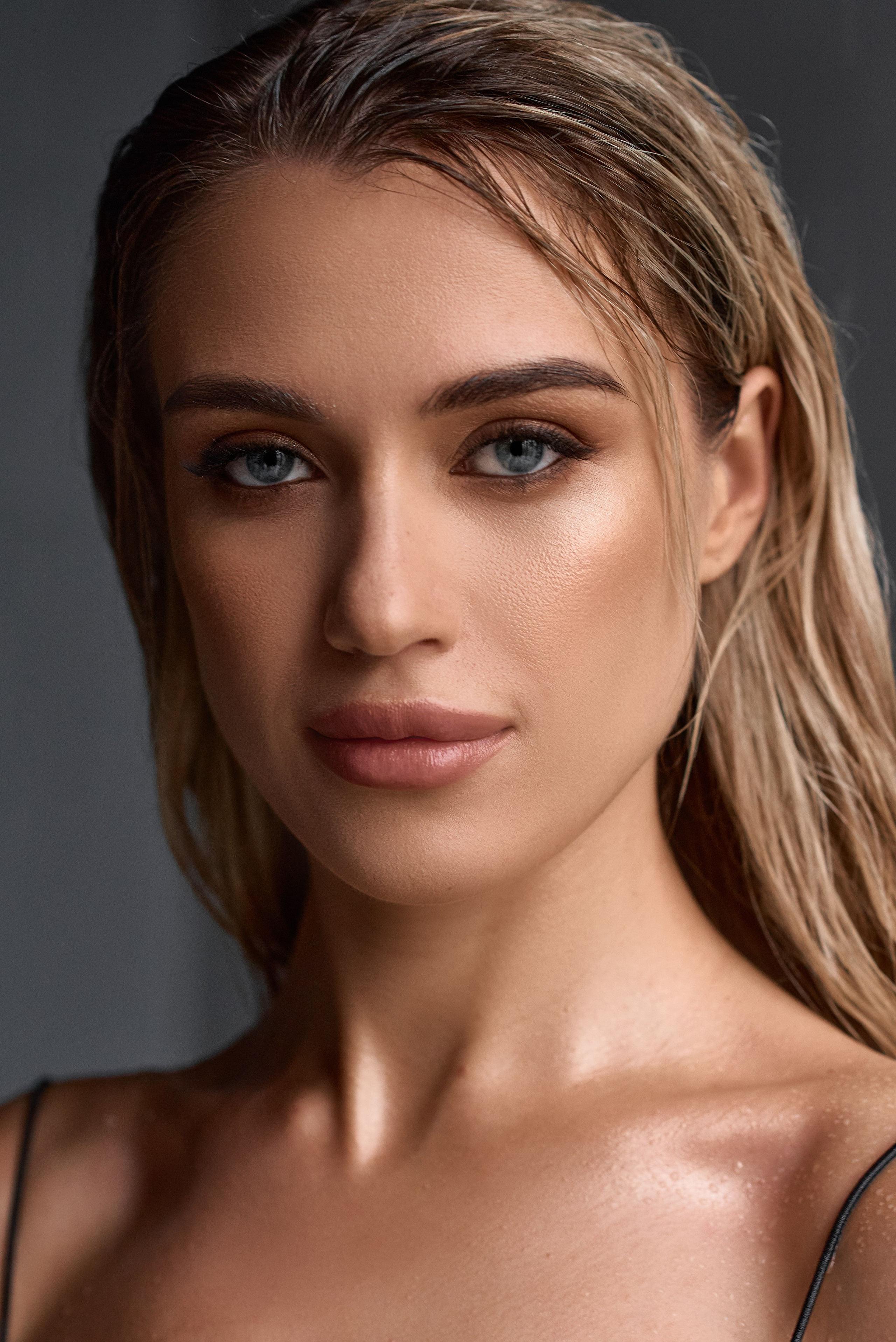 Чуттєвий портрет блондинки з природним макіяжем і вологим ефектом шкіри, знімок у контрастному світлі.